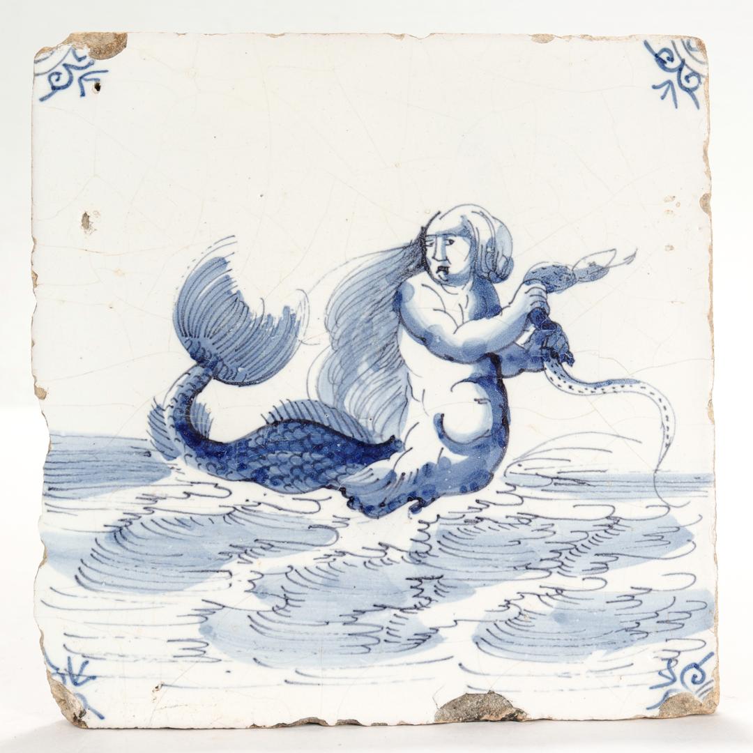 A fine antique 18th century Dutch Delft pottery tile.

Depicting a mermaid in the ocean wringing a snake with her hands.

Simply a wonderful Dutch Delft tile!

Date:
18th Century

Overall Condition:
It is in overall fair, as-pictured, used