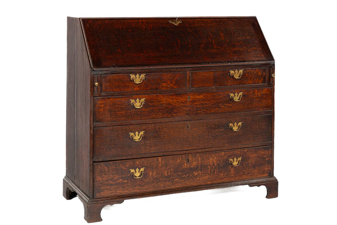 This English slant-front secretary, dating from around 1760–1780, is a fine example of Georgian craftsmanship. The case is constructed with quarter-sawn European summer oak, giving the piece its striking grain pattern. Over the centuries, the wood