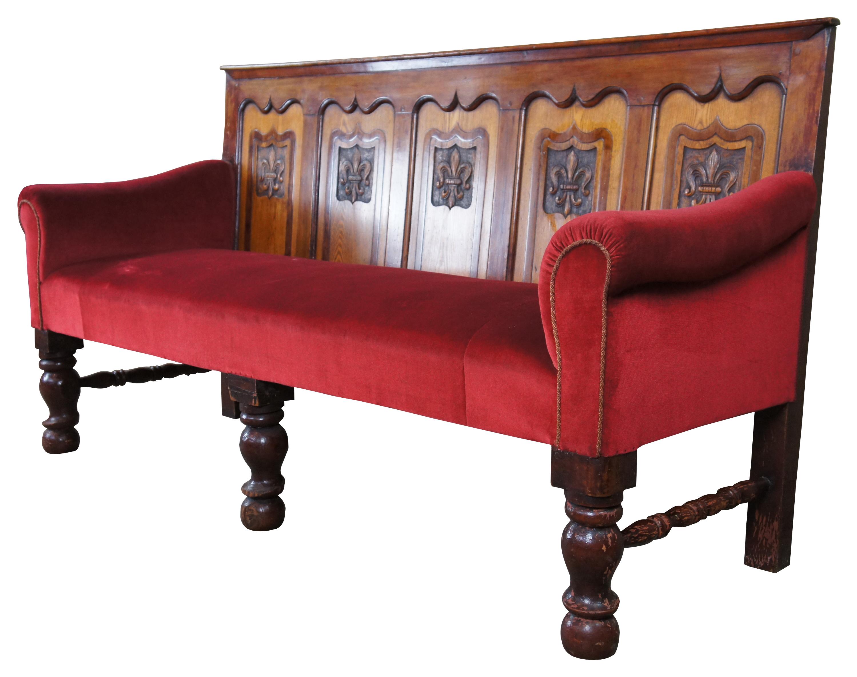 Extraordinary 18th century English oak pub bench or sofa.  A rectangular form with high back and red velvet upholstery.  Features Gothic revival panels and Fleur De Lis carvings.  The bench is supported by robust turned bun feet.  Origin London,