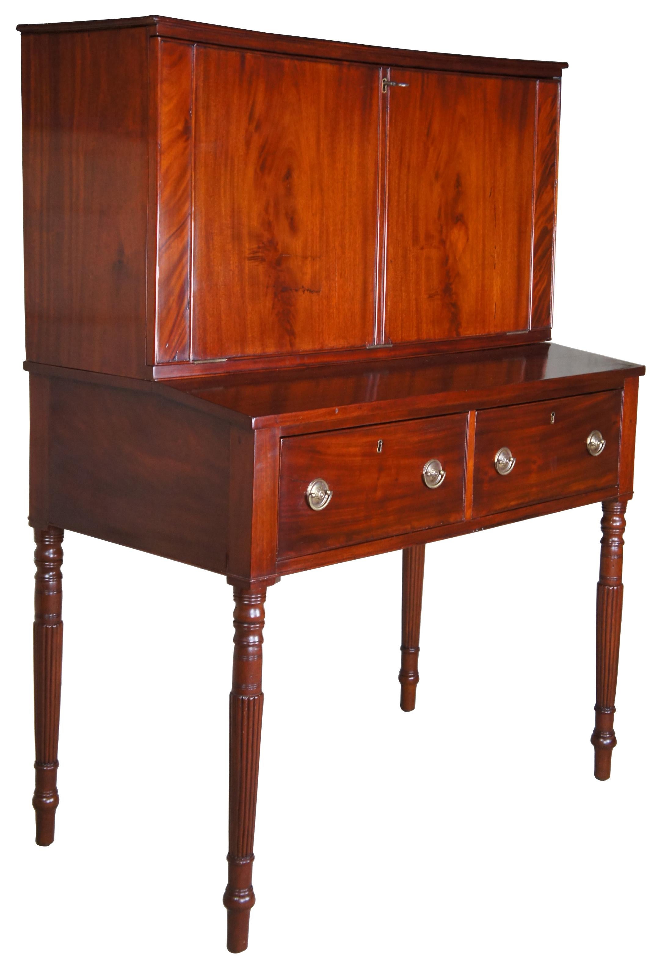 An exquisite and rare late 18th century American Federal Sheraton library secretary desk. Made of mahogany featuring velvet drop front writing surface that leads to multiple cubbies / compartments / cabinets (and one hidden), two large drawers with