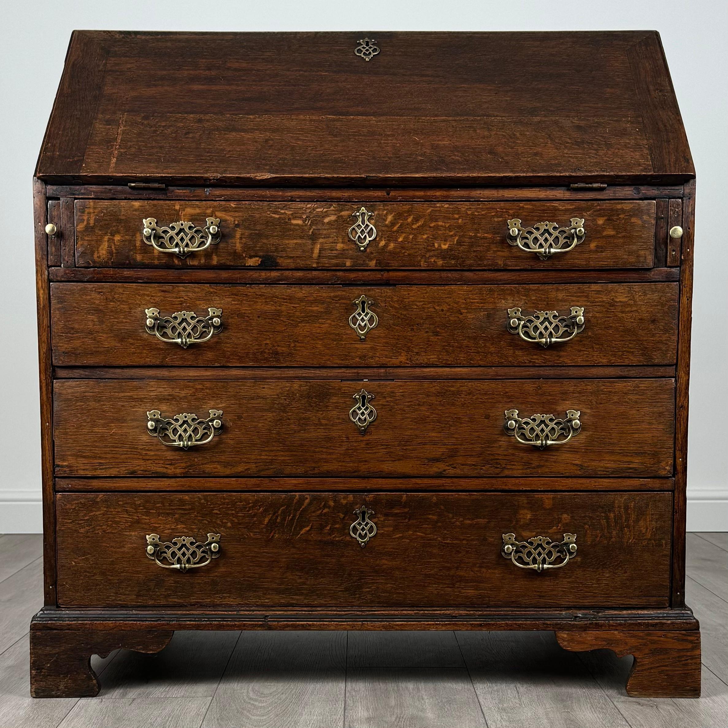 Questo splendido scrittoio antico in quercia del XVIII secolo è un superbo esempio di artigianato d'epoca, che unisce bellezza e funzionalità. Realizzato in rovere di alta qualità, il bureau poggia su classici piedini a staffa che gli conferiscono