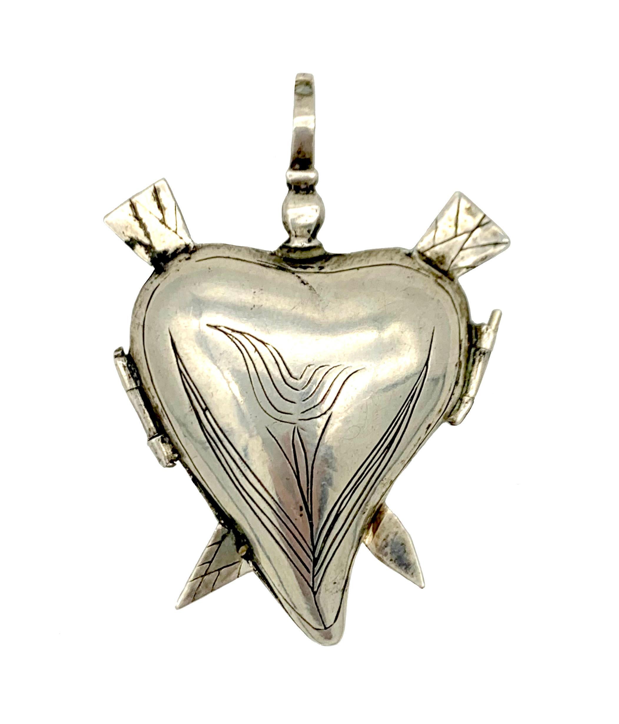 The hinged heart locket pierced y two arrows is closed my means of a silver pin.  