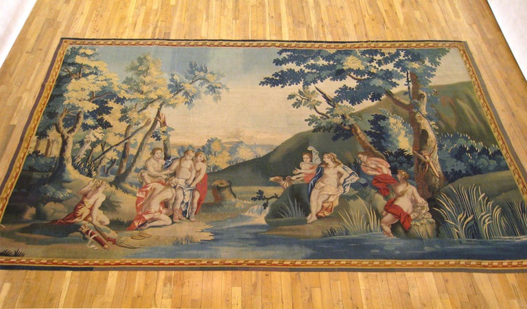 An antique Franco-Flemish mythological tapestry from the 18th century, featuring the goddess of the hunt, Diana with her attendant, Callisto. In this sultry scene, Diana reposes on a rock at right after bathing in a stream following a day's hunt.