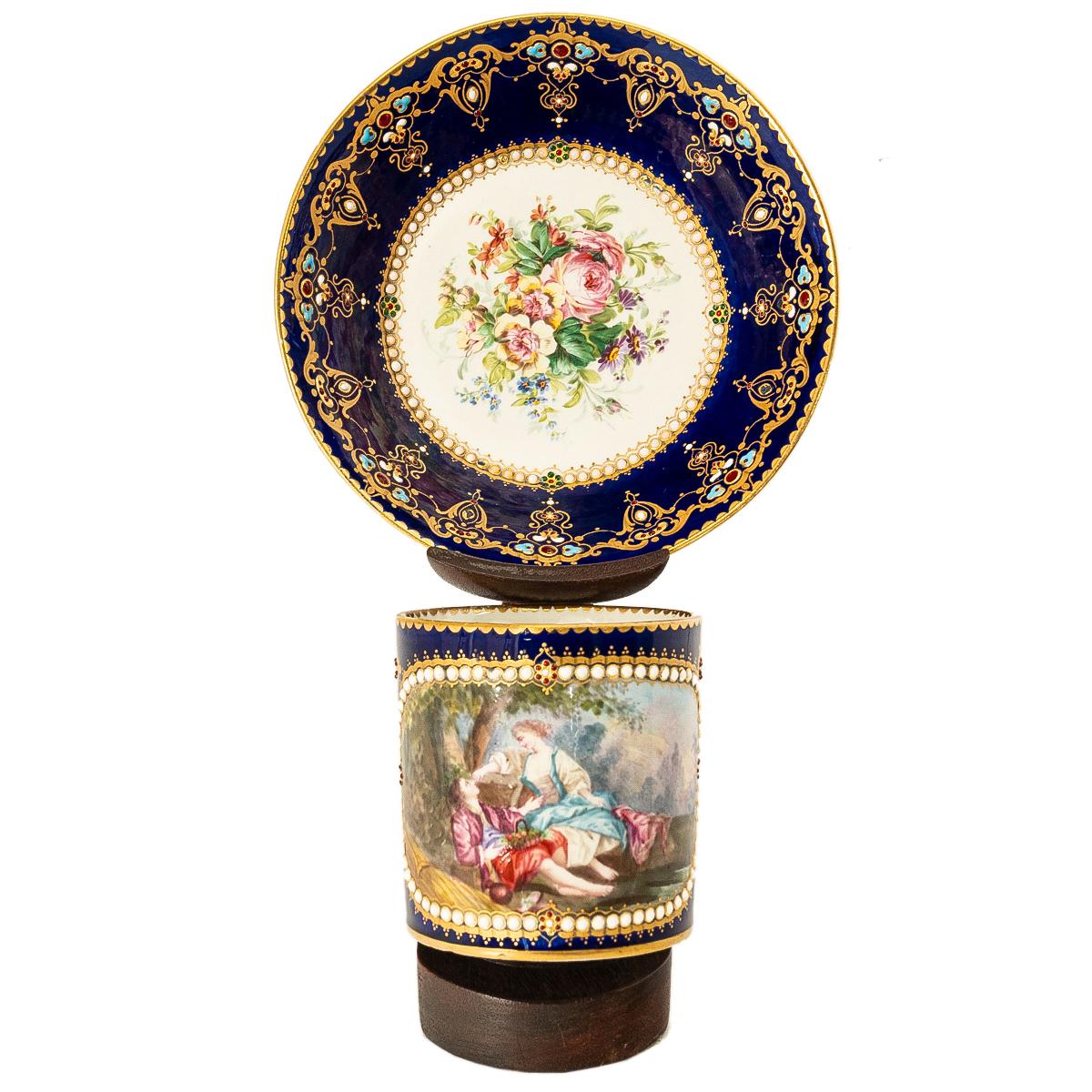 An 18th century Sevres blue ground cabinet cup and saucer with central Watteauesque style painted panel to the cup, within enamelled and jewelled style border, the saucer with painted floral spray. Both the saucer & cup with a painted blue
