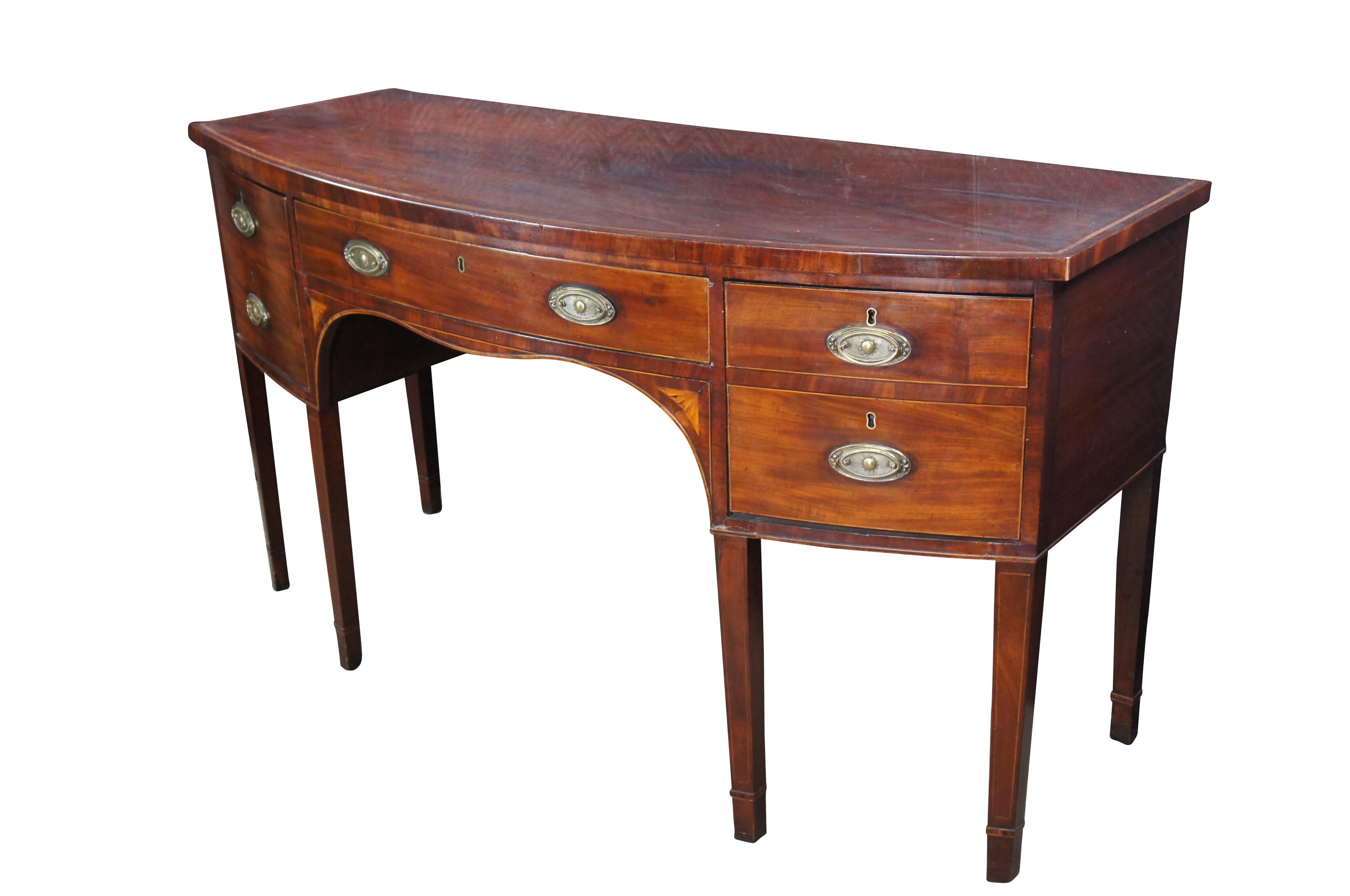 Late 18th Century George III Period Bowfront Sideboard.  Features a mahogany framed case with cross banding, inlay and striping throughout.  Includes a large central hand dovetailed felt lined drawer set bet between a felt lined cabinet along the