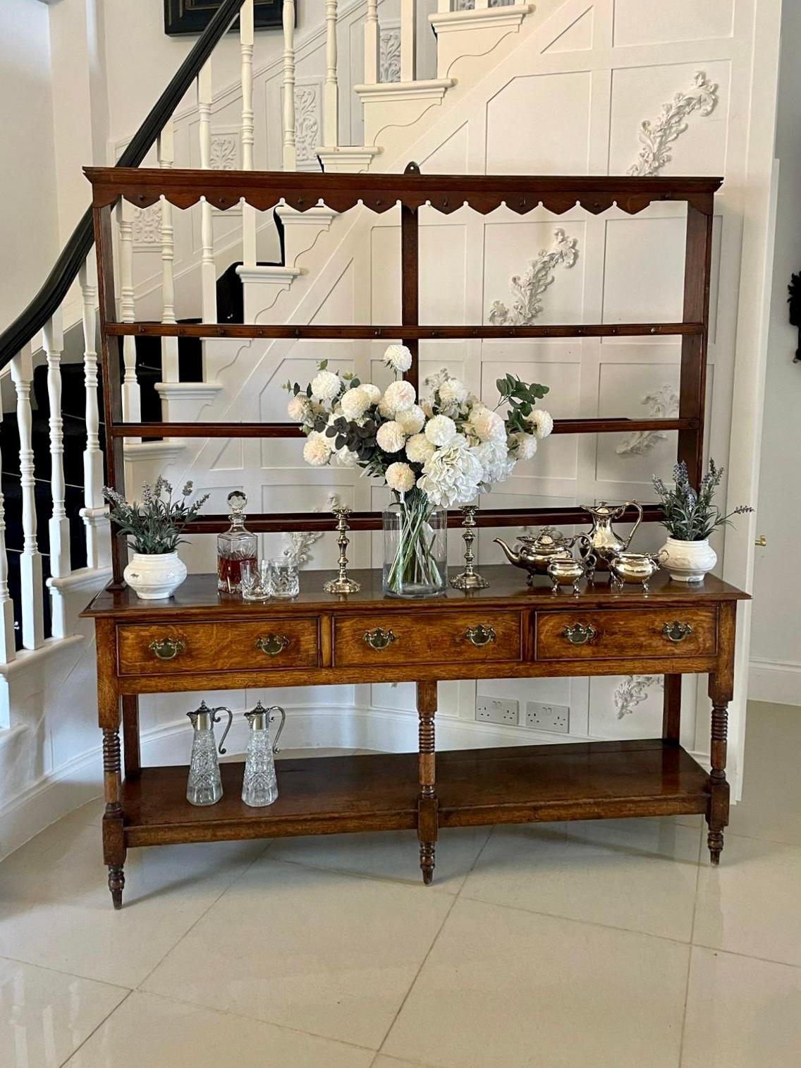 Antique 18th century George III quality oak dresser and original rack having the original oak plate rack with brass hooks above an oak dresser base with three cockbeeded drawers, brass handles, unusual turned column supports standing on turned legs