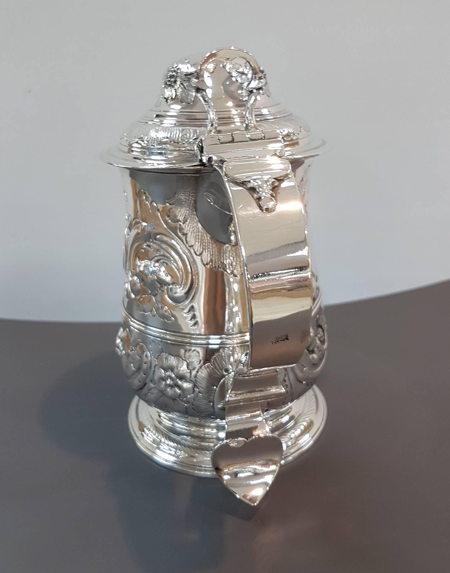 This is a wonderful antique English George III silver lidded tankard with hallmarks for London, 1765 and the makers mark of the renowned silversmiths John Payne.

The tankard has wonderful embossed floral decorations throughout with a blank