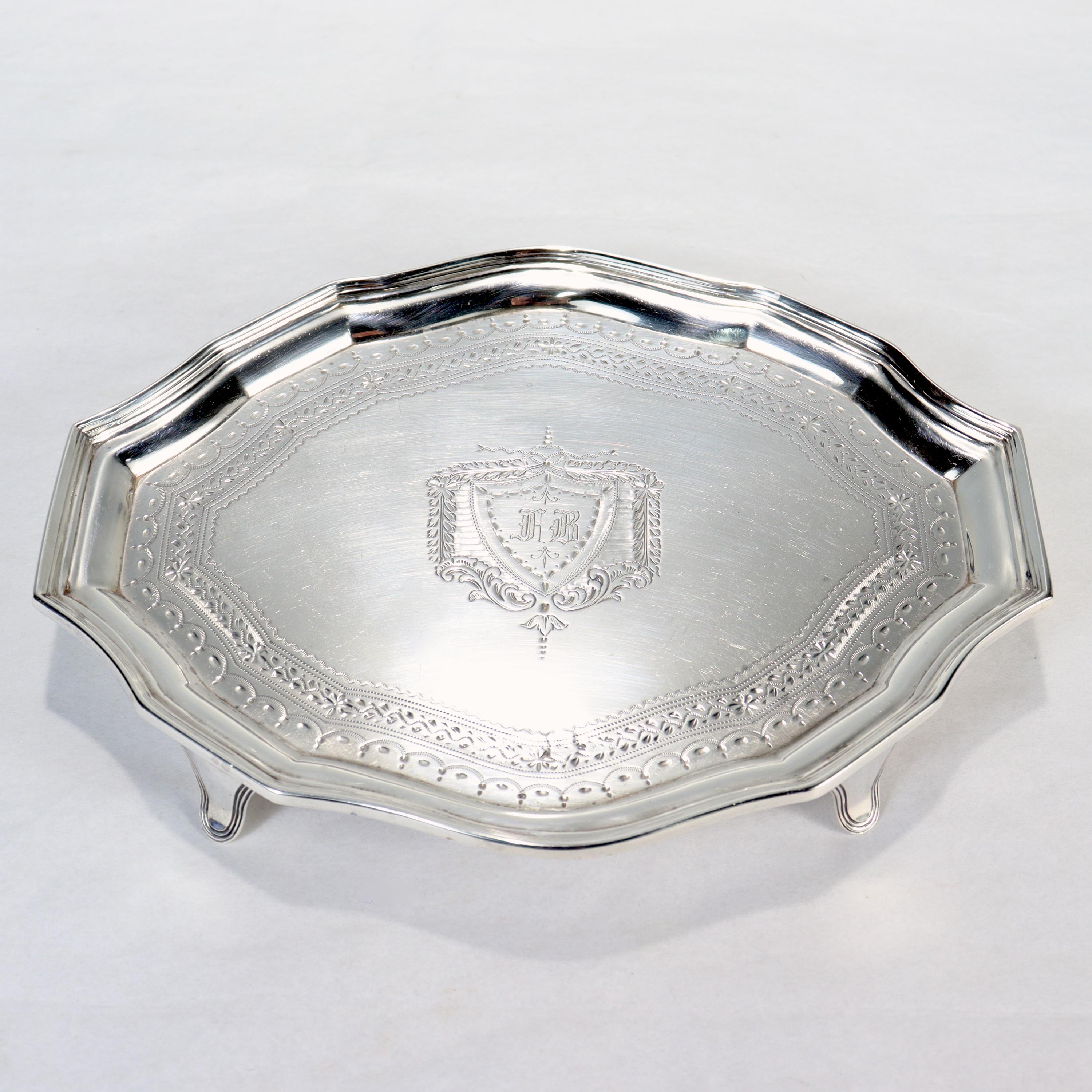 A fine 18th century Georgian sterling silver salver.

Supported by tab feet with a shaped top. 

With engraved decoration including a shield shaped cartouche at its center with a monogram. 

Simply a great Georgian style silver