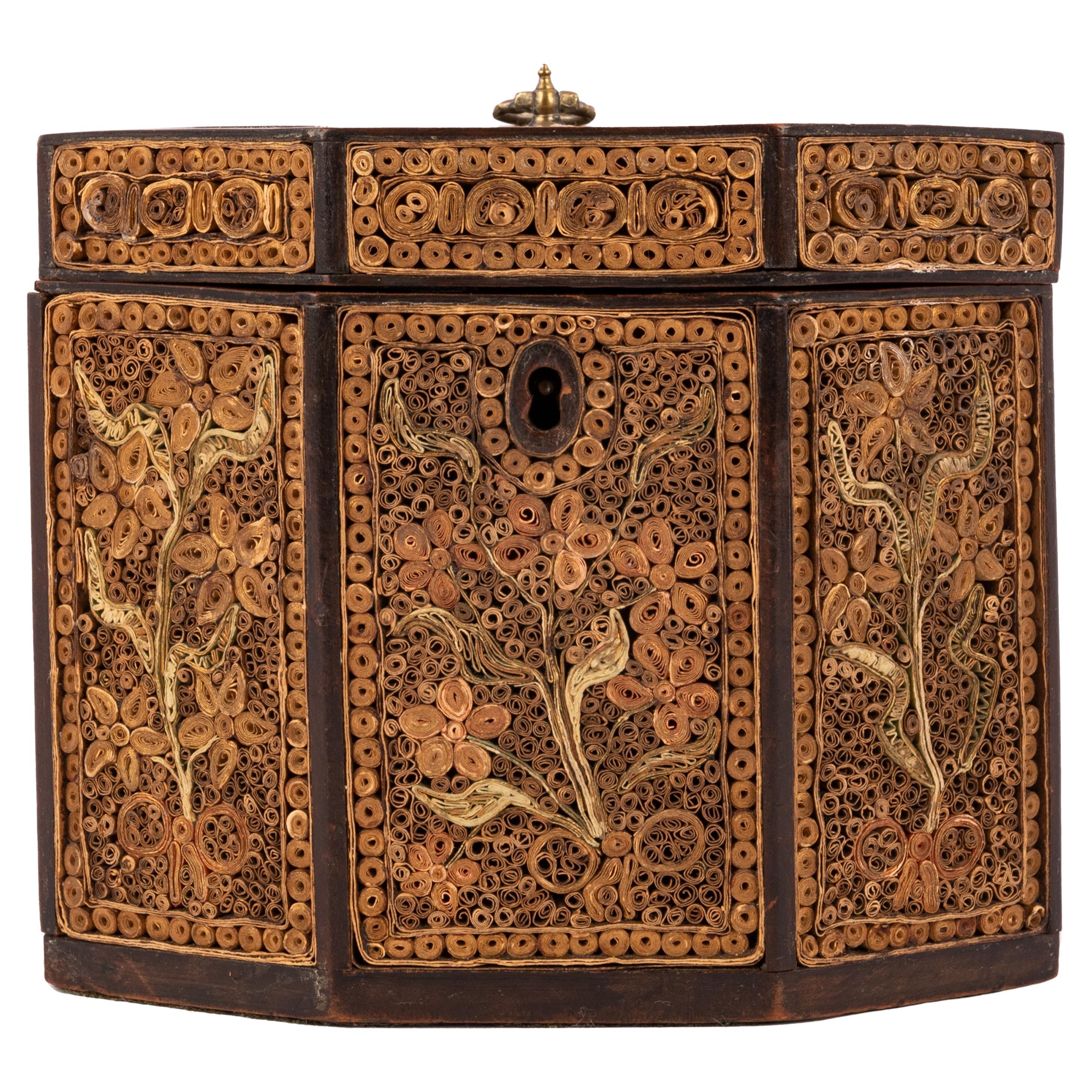 A good antique Georgian scrollwork tea caddy, circa 1780.
An octagonal shaped paper scroll tea caddy, the front, back and cover decorated overall with paper scrolls in stylized floral and foliate motifs. The caddy having a hinged lid with an