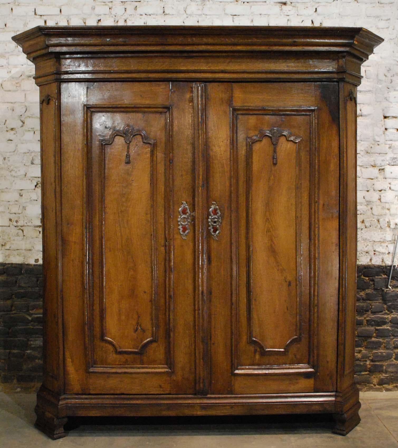 A beautiful antique German cabinet that was in the German state of Westphalia circa 1750.
The cabinet has two doors with raised panels and elegant hand carved ornaments, flanked by two angled corners. The cabinet is made in solid oak and can not be