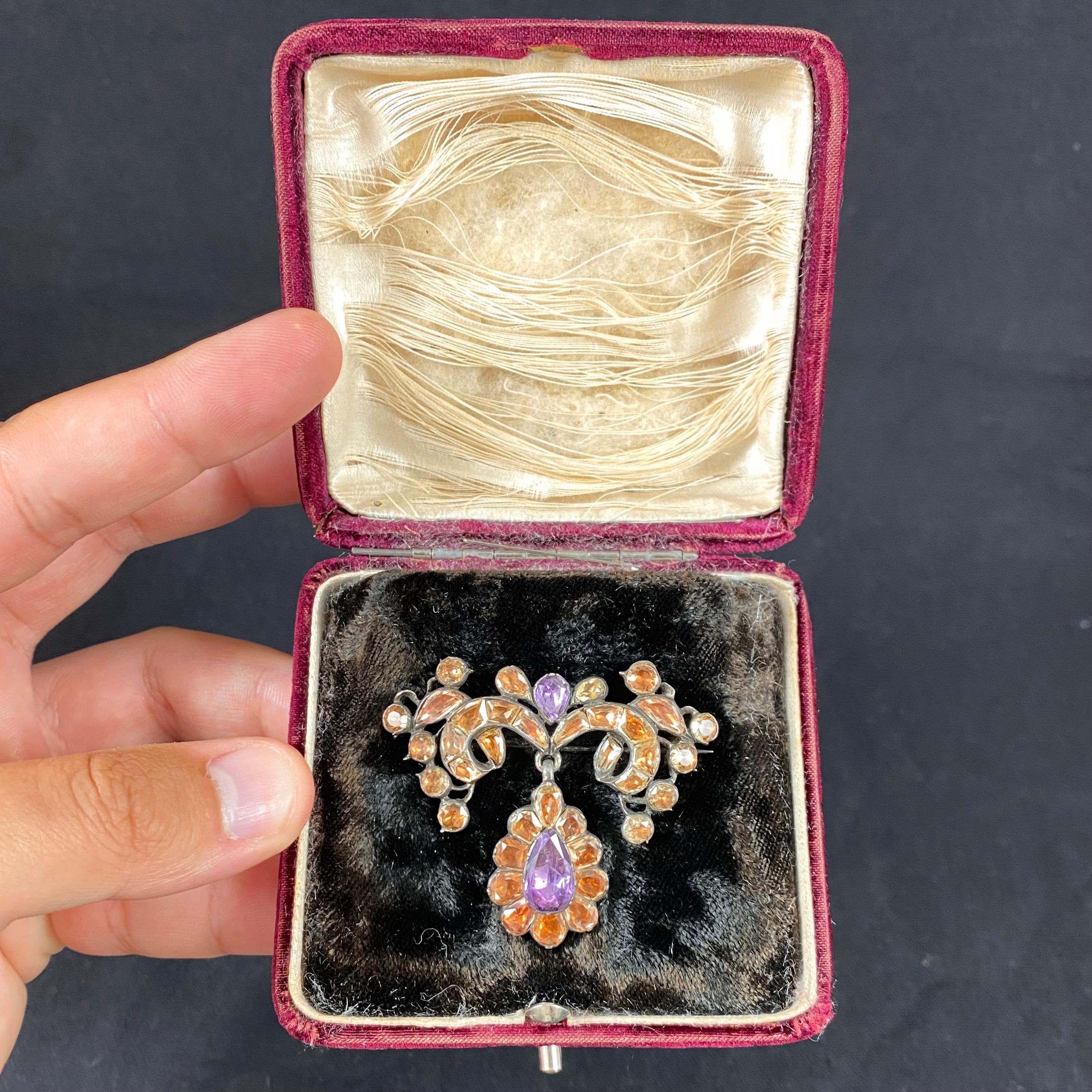An antique 18th century foiled imperial topaz and amethyst brooch in silver, Portuguese, circa 1770. From the Georgian period, this brooch is designed as two openwork scrolled foliate branches issuing from the center, where hangs an articulated