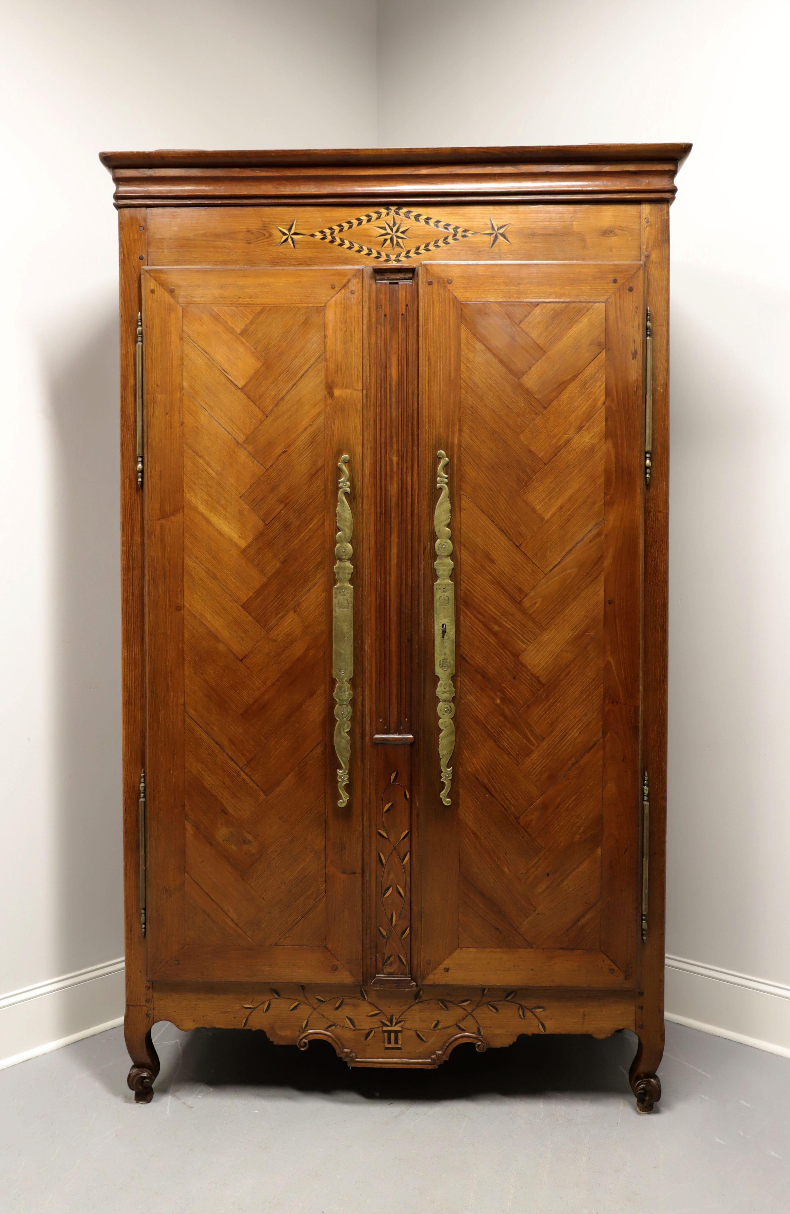An antique French Country Louis XV style armoire, unbranded, from the 1700's. Handmade of walnut with brass hardware. Features crown molding, lockable double doors with beautiful inlaid parquetry detail, marquetry design to top, center panel &