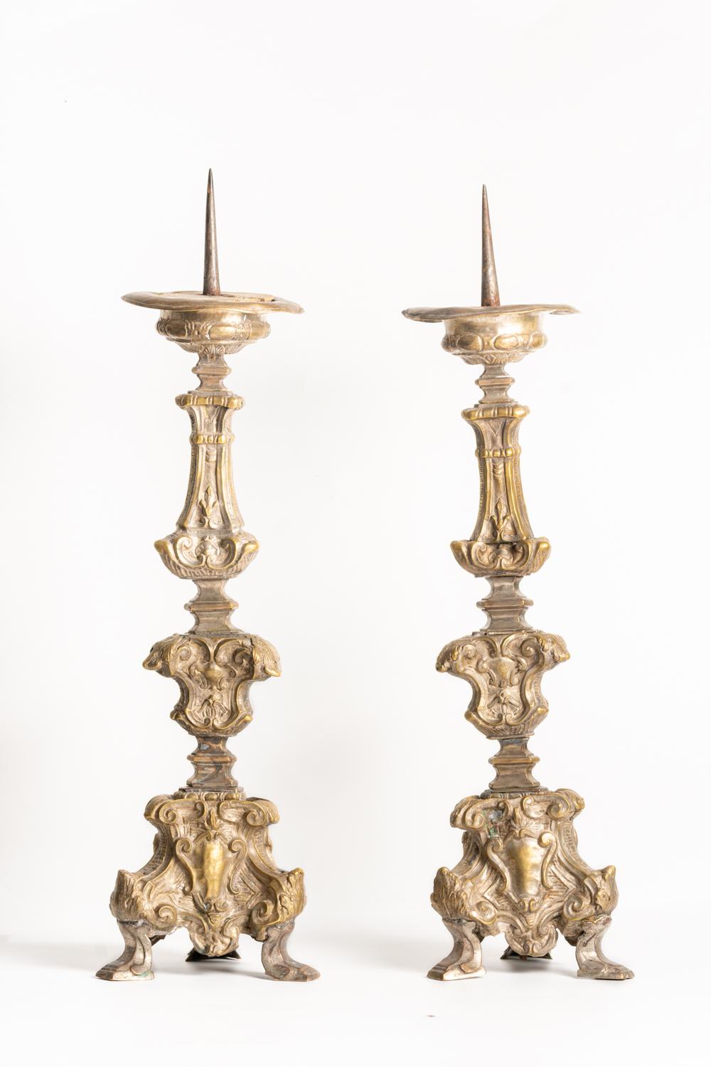 A fine pair of 18th century Italian brass pricket candlesticks impressively decorated in a baroque style with knopped stems and triform bases decorated with cartouche and foliage alterations. The columns are beautifully ornated on each side with