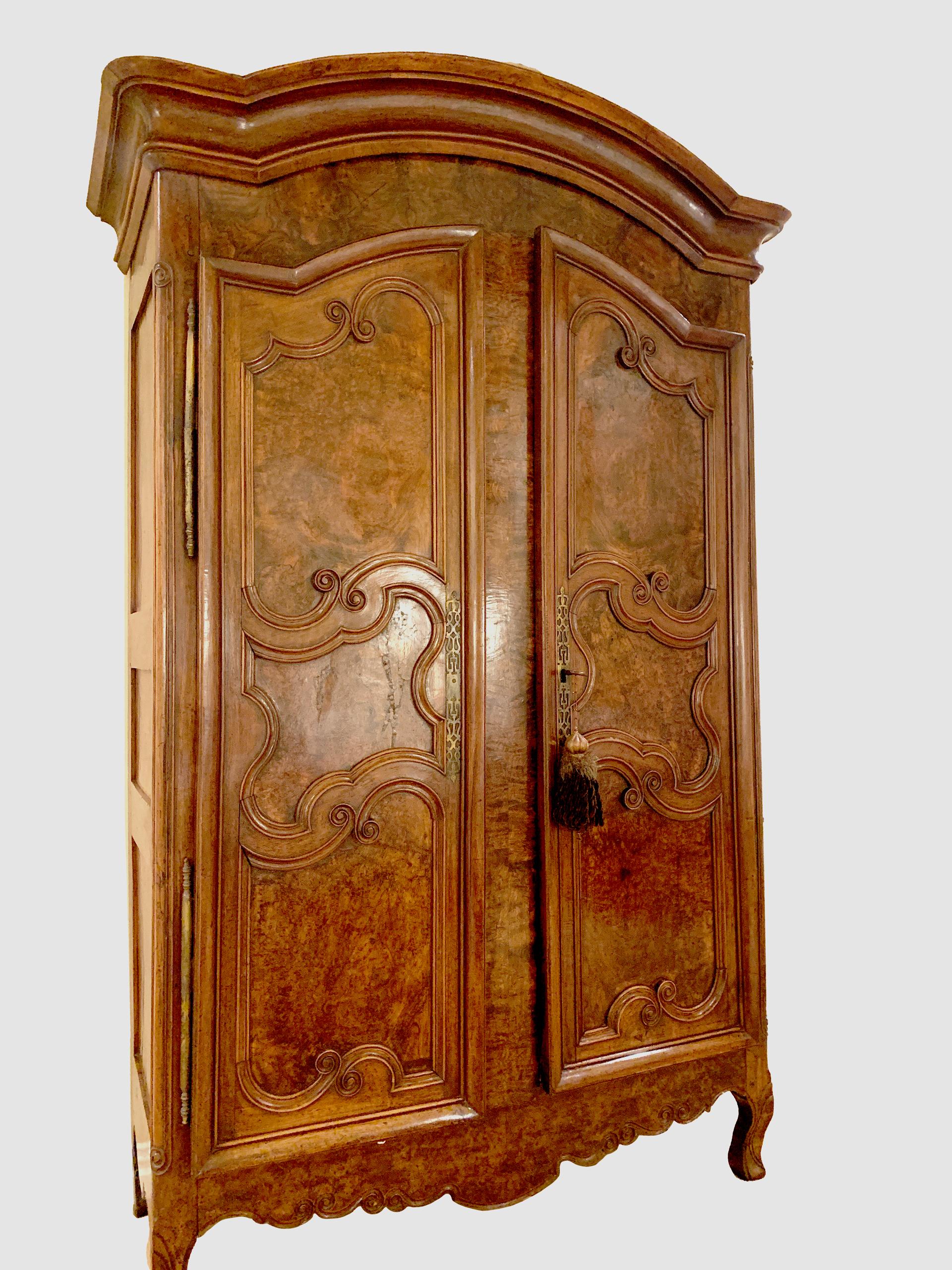 An exceptional 18th century French period Louis XV armoire handcrafted of indigenous old growth walnut and burled walnut in the typical technique mastered by the skilled artisans of France, circa 1750s. This large provincial armoire features a