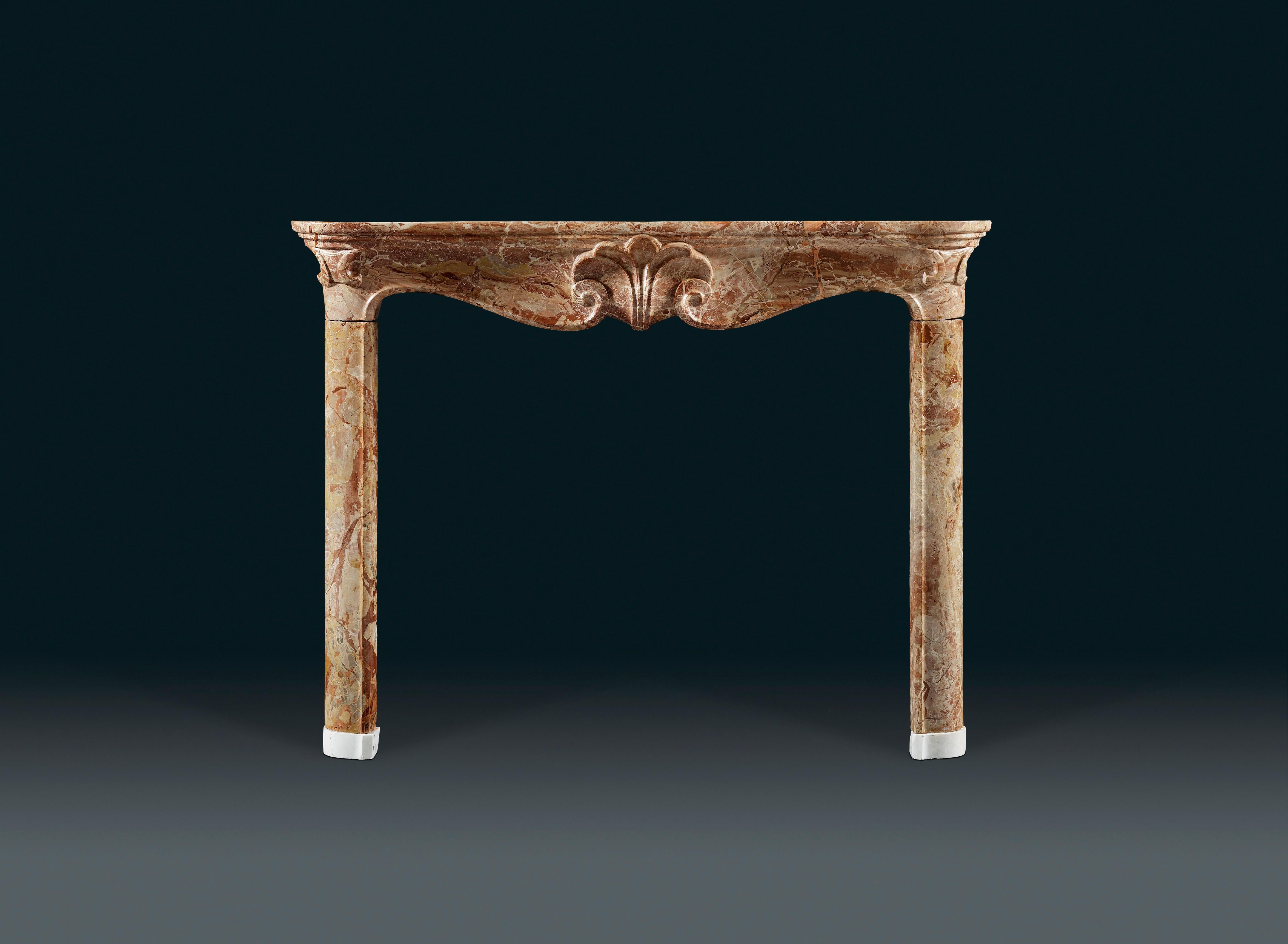 An 18th Century Louis XV mantle in Jasper marble, the curved shelf above a serpentine frieze carved in the solid, centred by a floral motif. The whole on elegant Statuary marble footblocks