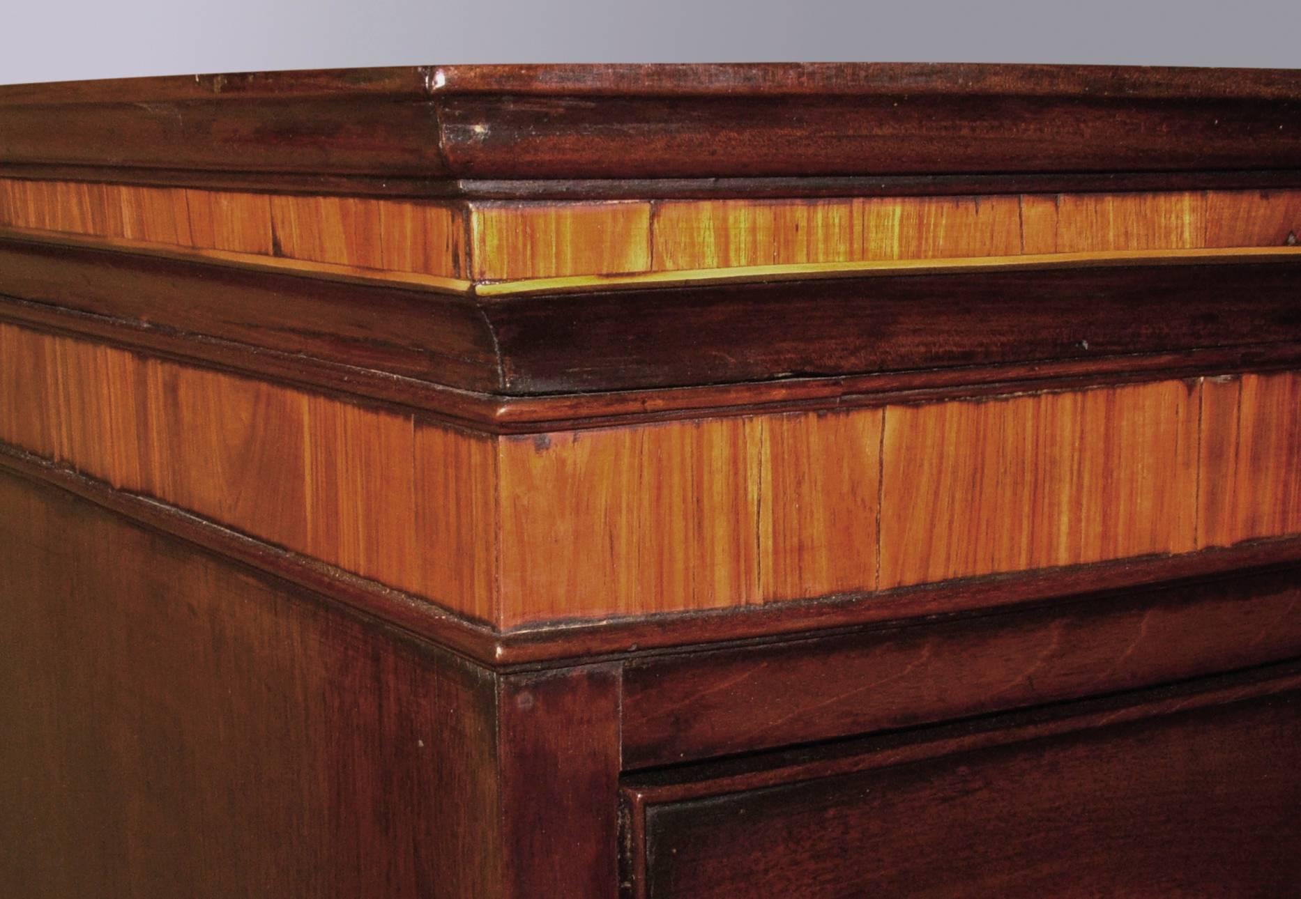 A George III period figured mahogany bow-fronted tallboy of attractive small proportions, having moulded and kingwood crossbanded cornice above seven cock beaded drawers supported on splay-leg base with shaped apron.