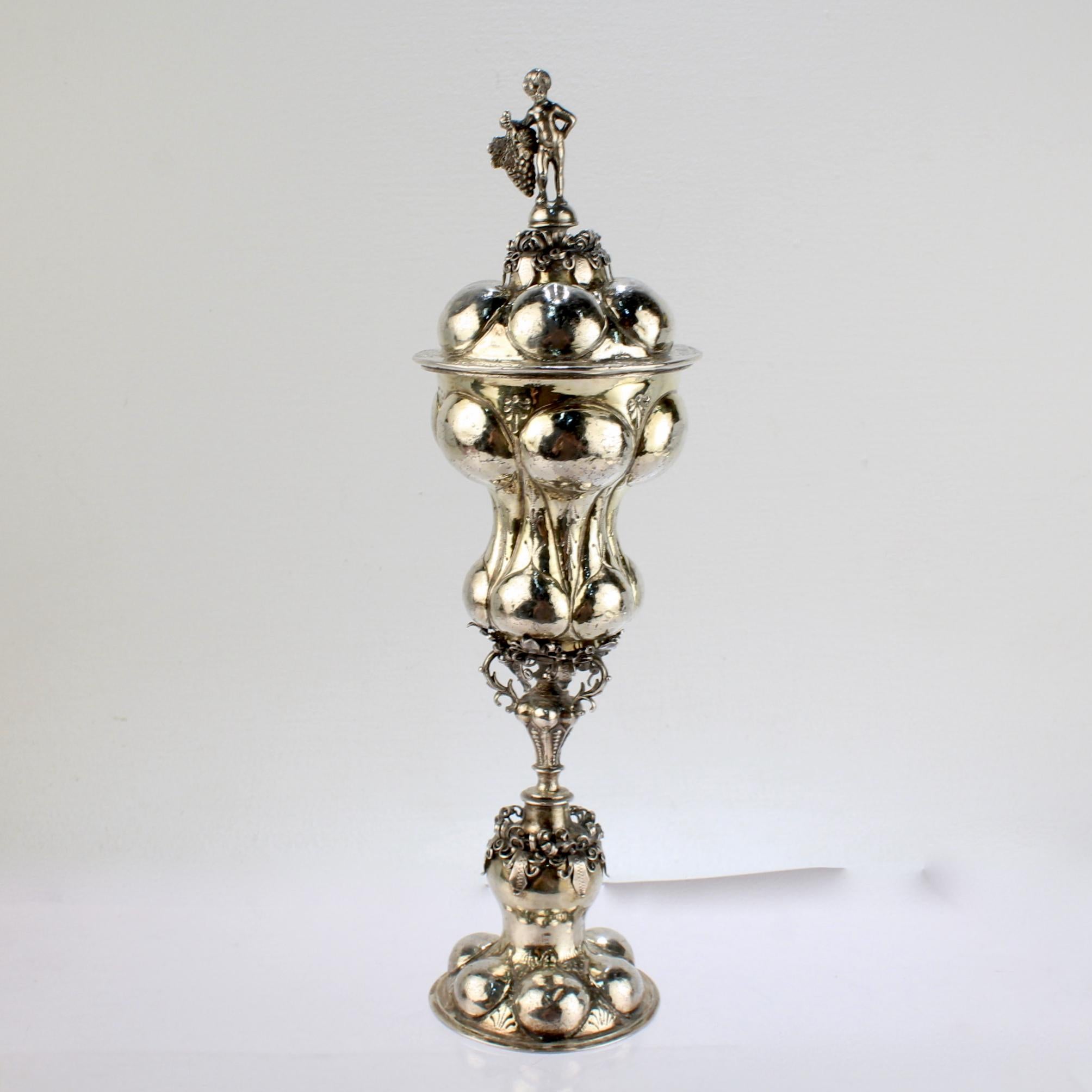 A fine antique German lidded chalice or pokal.

Struck with an N likely for Nürnberg (or Nuremberg).  

With a lobed foot and ornate pedestal stem supporting a conforming cup & lid and surmounted by a full figural putti finial. 

There is hand