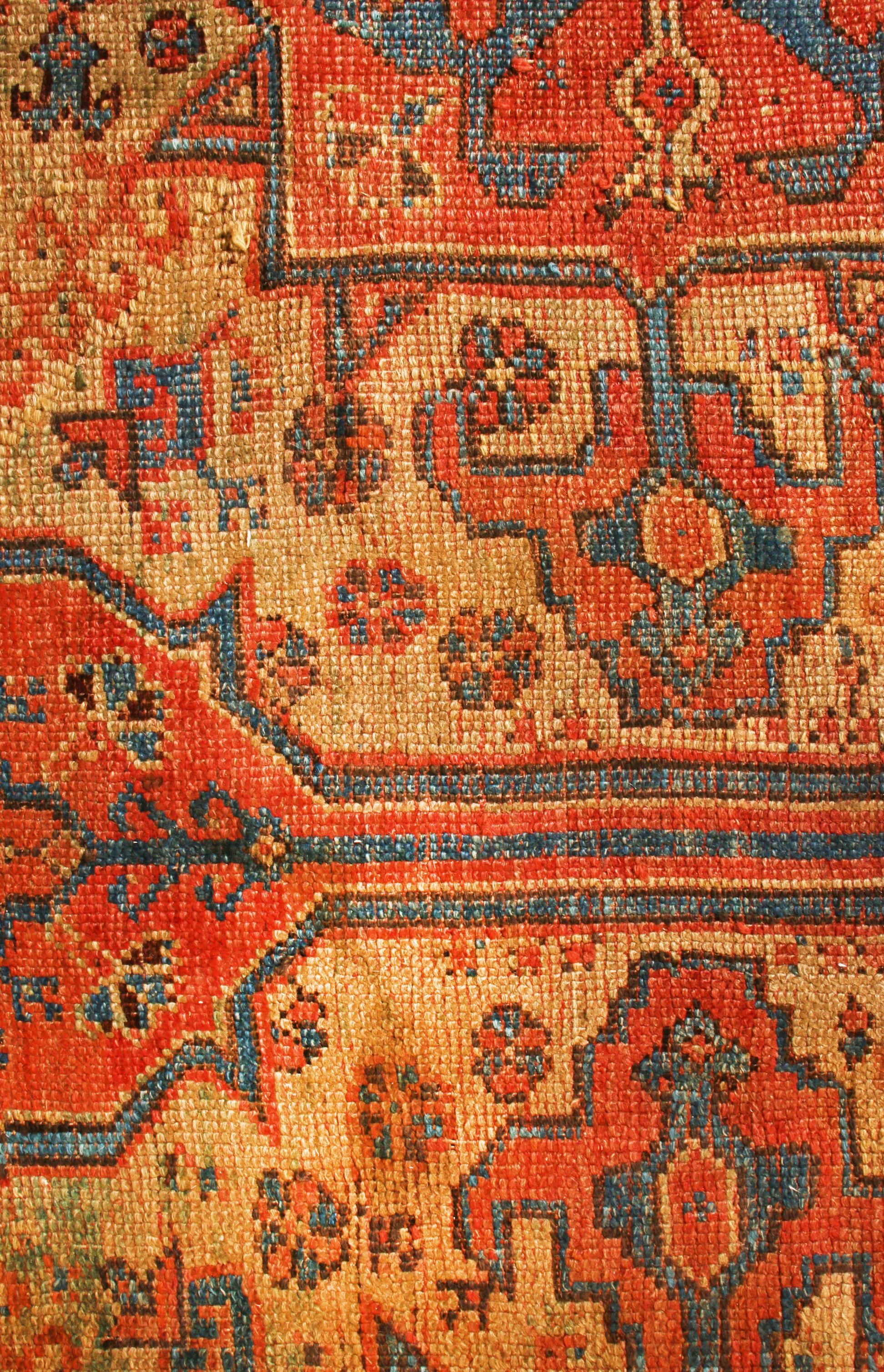 Originating from 18th century India, this antique traditional Oushak rug has an expansive series of floral and gul imagery in a lustrous, hand knotted wool portrait. Featuring an especially unique colorway combination of bright sunset orange, beige