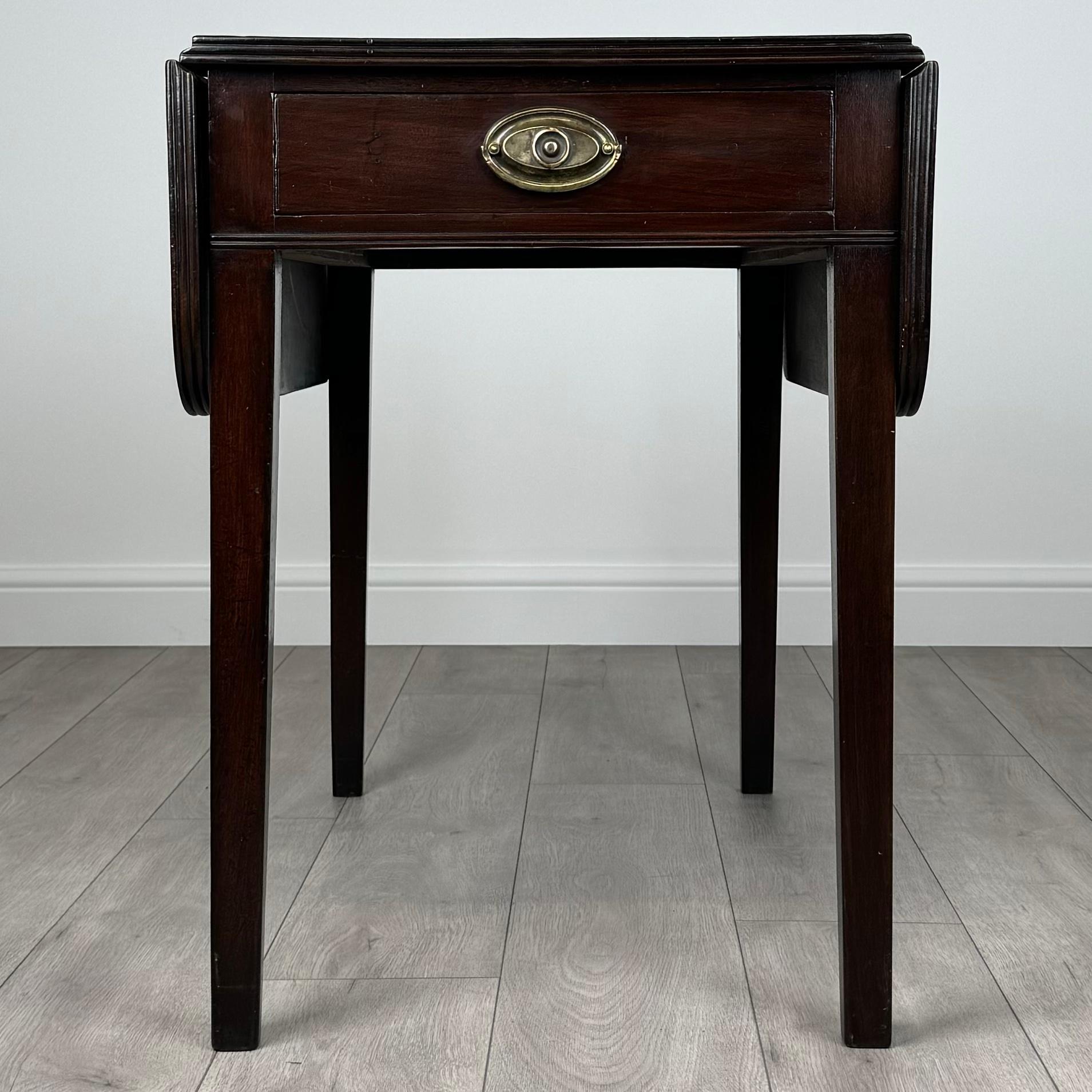 Cette table Pembroke antique du XVIIIe siècle est un bel exemple de design géorgien, fabriqué dans un riche acajou. Il repose sur d'élégants pieds fuselés et comporte un seul tiroir doté d'une poignée en laiton d'origine, ce qui ajoute à la fois au