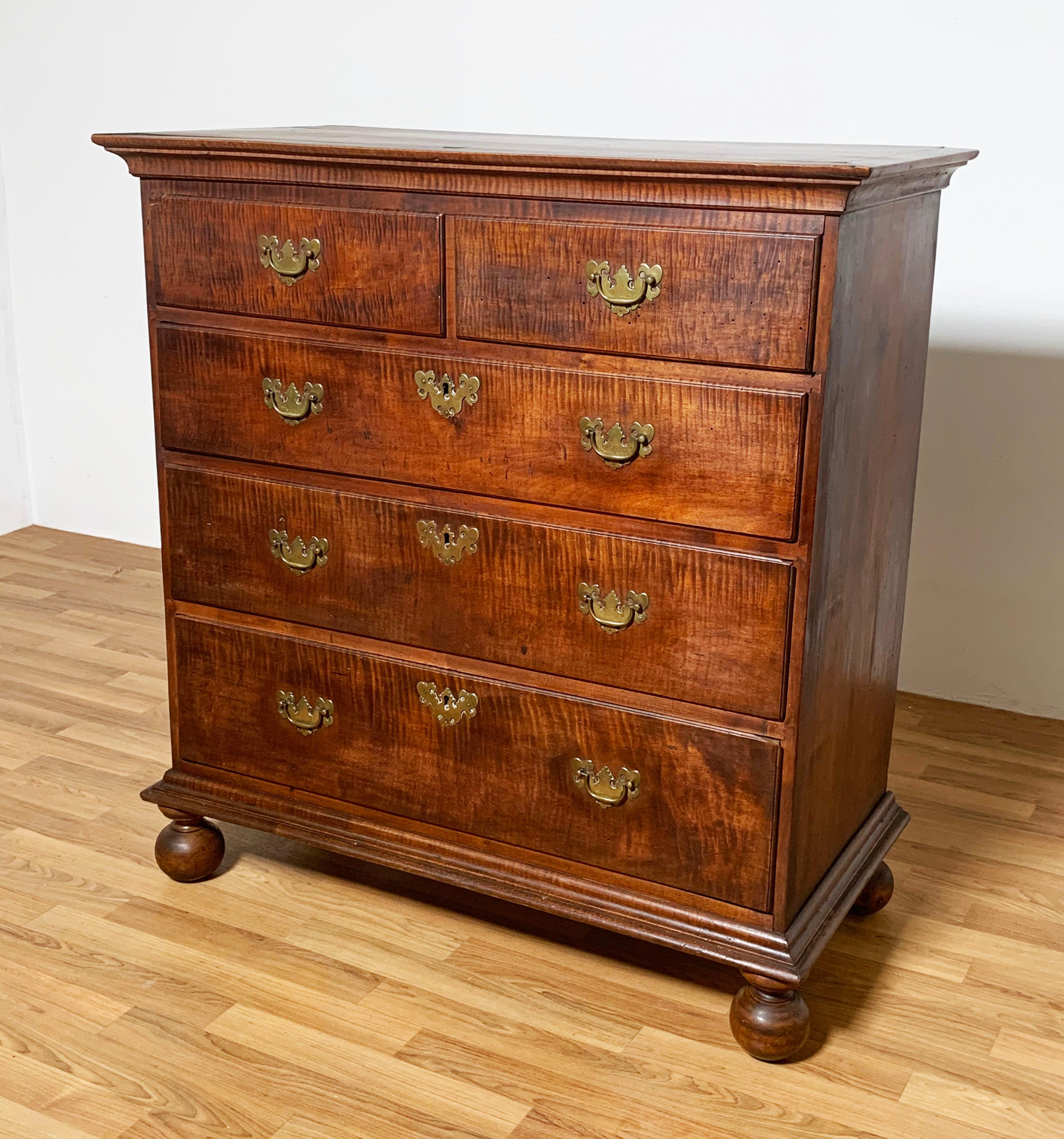 Antique 18th century Rhode Island chest in flamed maple on ball feet with original brasses, ca. 1740. The construction of two flanking drawers over three of graduated size and the top and bottom moldings are a striking feature of this early American