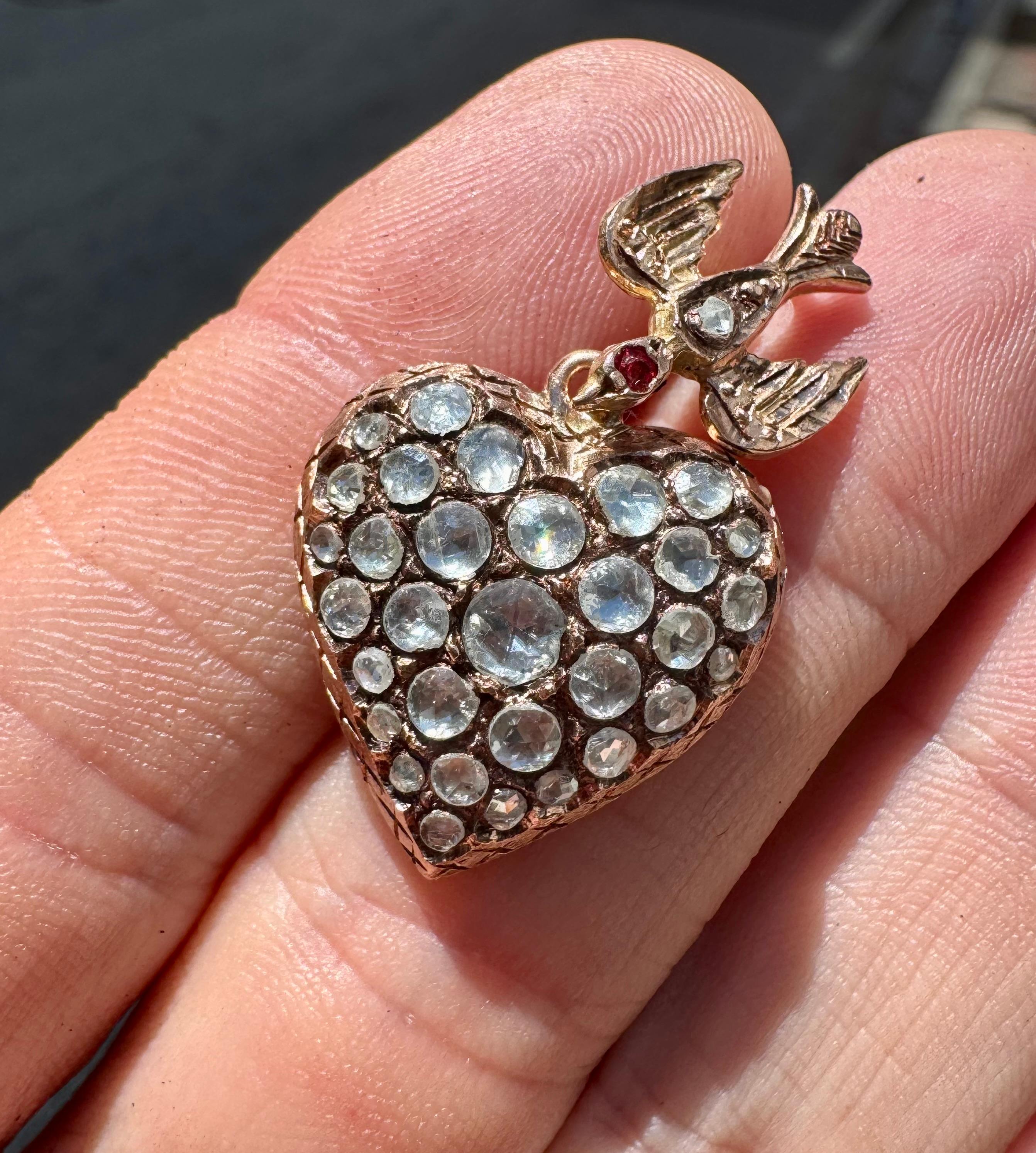 Bellissimo ciondolo a forma di cuore gonfio ornato da diamanti naturali taglio rosa estratti dalla terra. Questo antico tesoro è ricco di dettagli: un uccello passerotto pende sopra questo elegante cuore con diamanti incastonati. 
L'incisione è