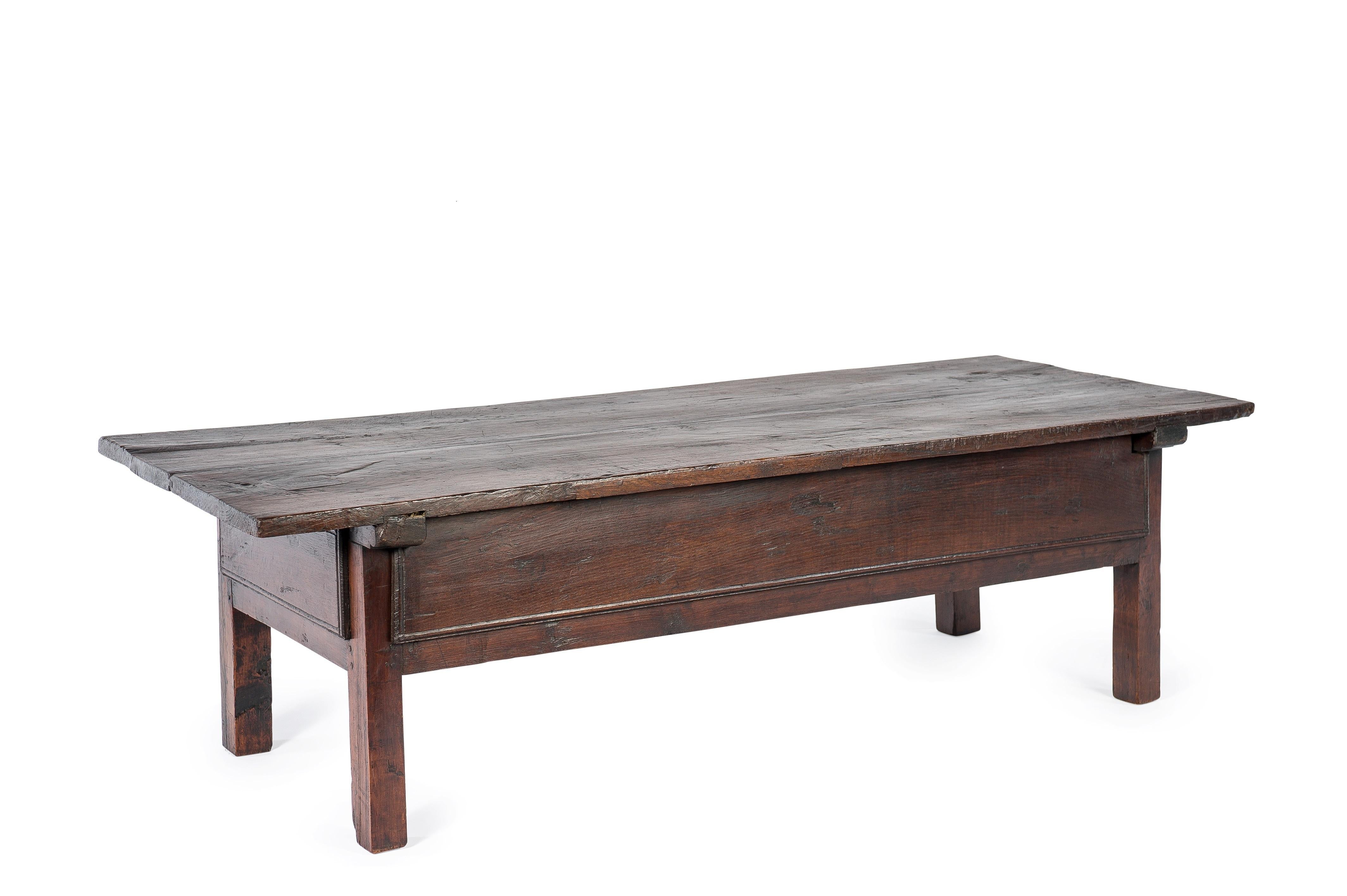 This beautiful dark brown rural coffee table or low table originates in Spain and dates circa 1760. 
The table has a beautiful top that was made from two boards of solid chestnut wood. The top has a beautiful patina and shows the many marks of use