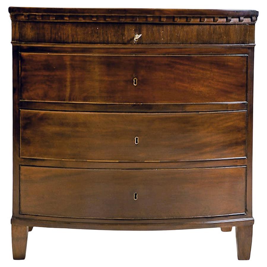 A handsome and unusually small Louis XVI chest in mahogany offering four drawers with bowed front, and featuring a fluted tambour molding on the top drawer resting under characteristically 18th century dental molding. Scandinavia fell in love with