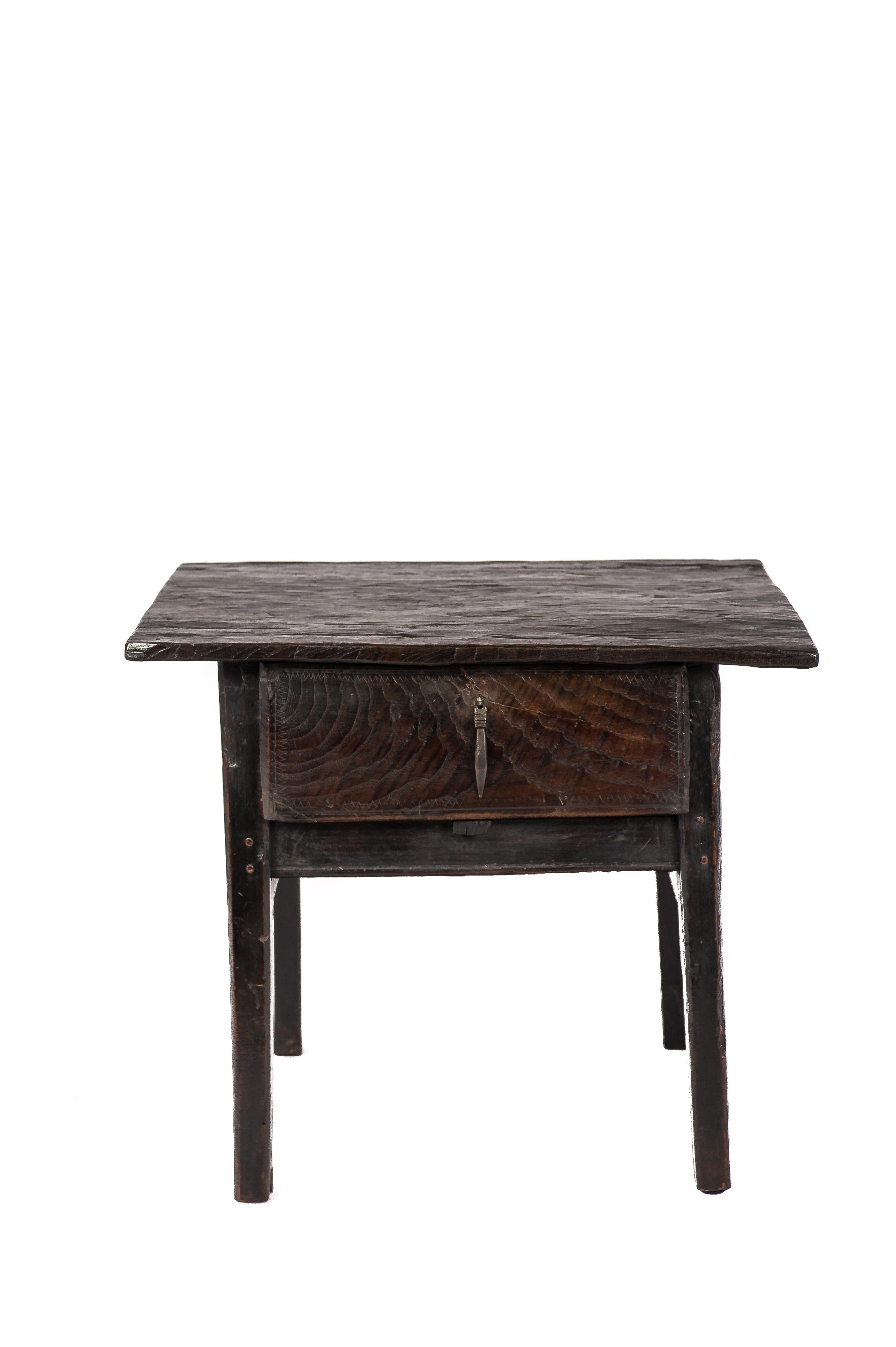 A beautiful antique side table or occasional table that was made in rural Spain circa 1750. The solid hand-carved chestnut rectangular top was made from a single board of wood and was jointed to the base by forged steel nails. The table features a