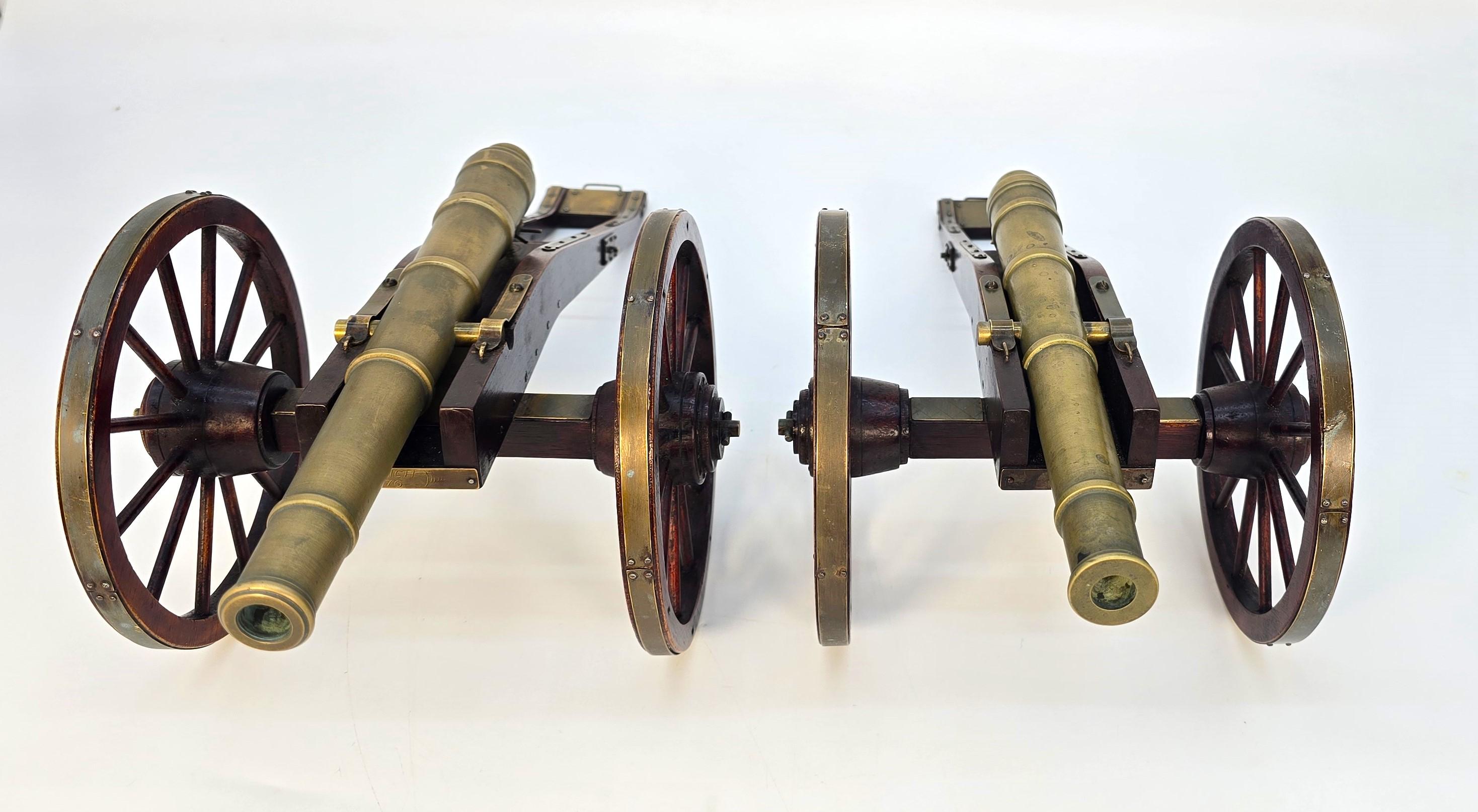 Cette superbe paire de canons de bureau a été magnifiquement fabriquée à la main en acajou, avec des ferrures en laiton clouées et de lourds canons en bronze moulé. L'attention portée aux détails de ces canons miniatures est superbe. Ils sont dotés