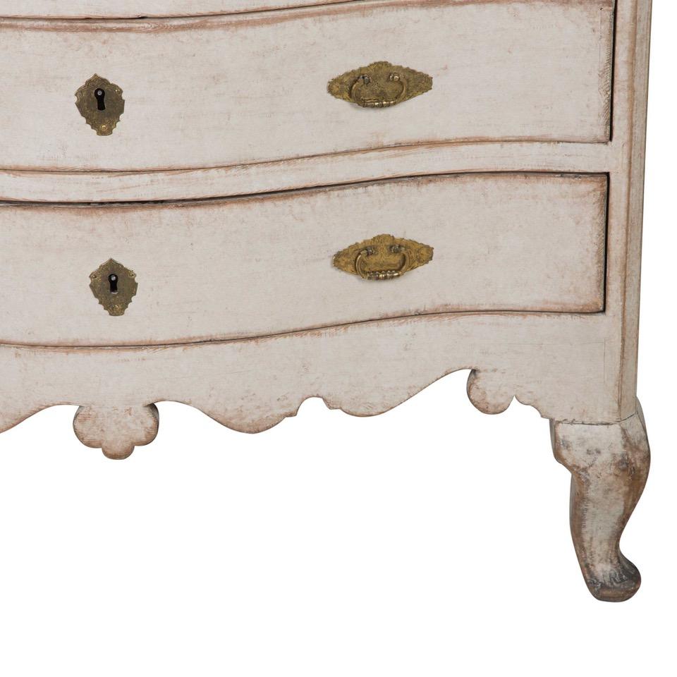 This antique Rococo commode was manufactured in Sweden in 1760. The commode features three drawers with their original handles - two apiece, and a keyhole for each drawer. This piece has a gentle curved shape, with elegant tapered legs and carved