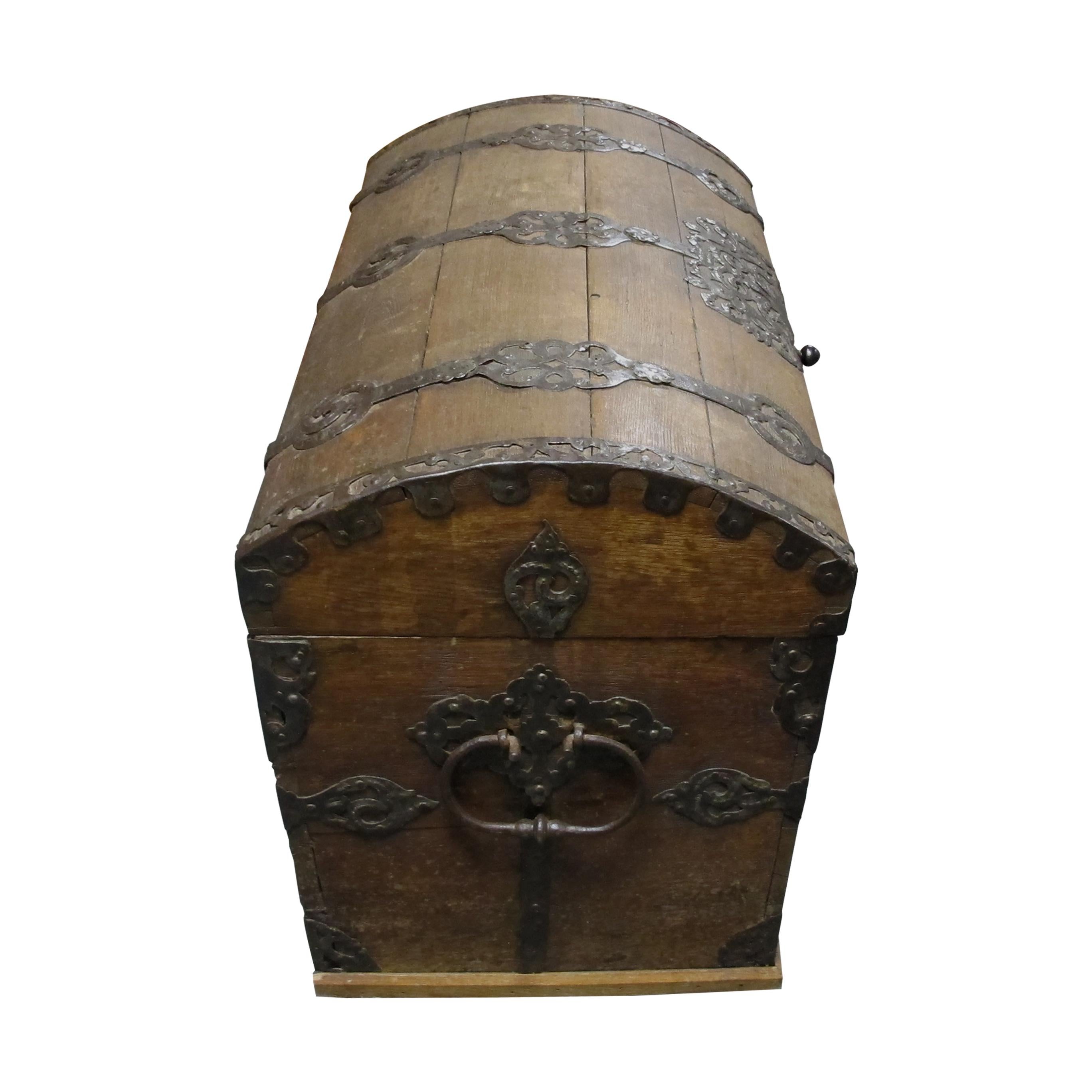 Magnificent Baroque trunk-coffer made of solid oak with a dome curved lid top which is decorated with iron ribbons ands and foliage. The original key and the lock mechanism are in perfect working condition. Each side of the trunk is fitted with iron
