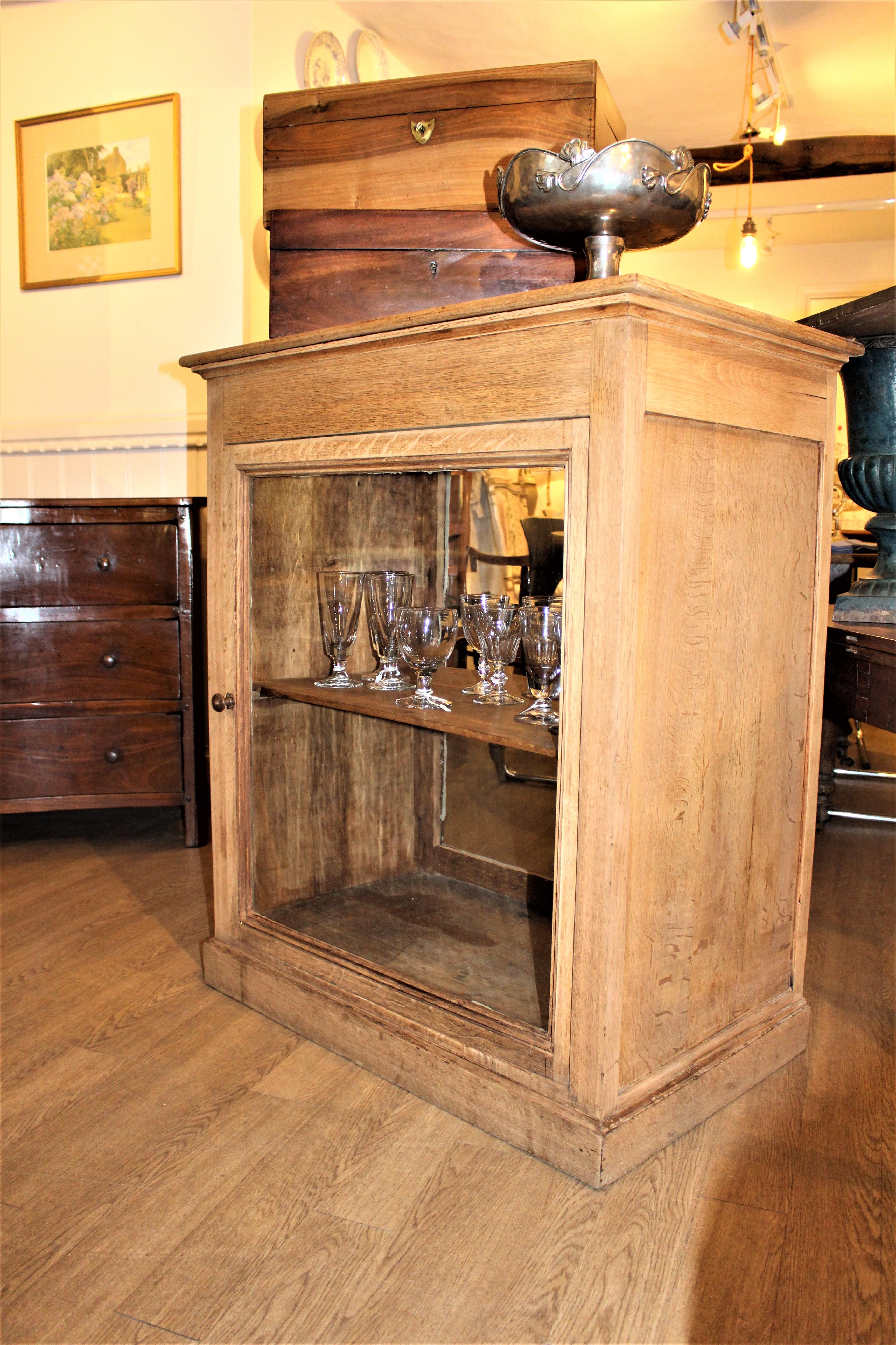 This French shop counter was dark oak and has recently been bleached. It has a storage compartment under the lid, and a glass door with the original rippled glass at the front.
There is a removable shelf inside and glass on the back too (not