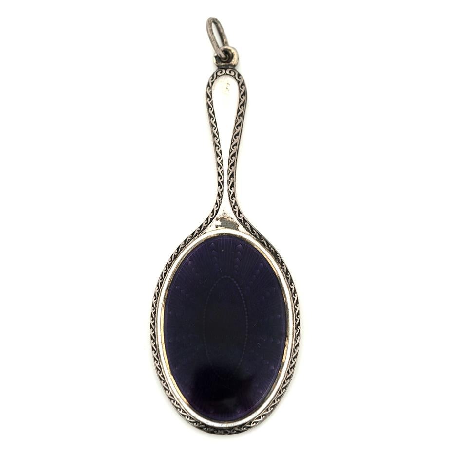 This elegant antique chatelaine mirror dates to the late Victorian or early Edwardian period, when personal grooming items were worn at the waist as both fashion and function. Crafted in silver and detailed with exquisite purple guilloché enamel,