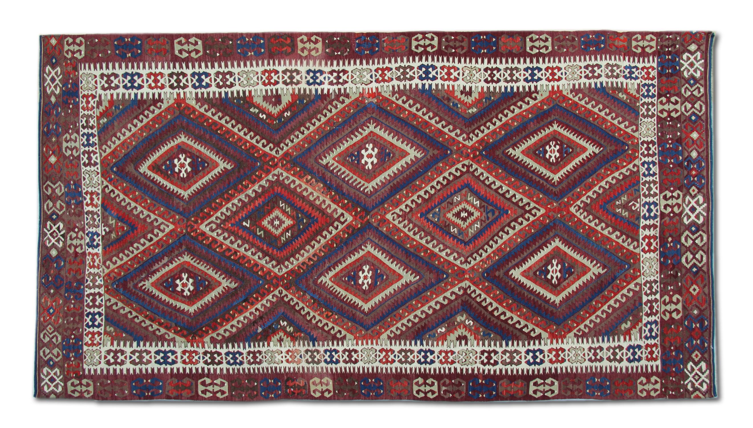 Dieser antike anatolische Kilim-Teppich aus dem Jahr 1900 ist ein bemerkenswertes Beispiel für handgefertigte türkische Stammesweberei. Er weist ein kühnes geometrisches Rautenmuster auf, das die Kunstfertigkeit der frühen nomadischen Flachgewebe
