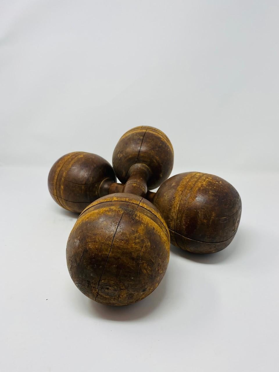Antique and with patina, pair of late 19th century wood dumbbells with fine carved detailing rings in the middle and on the ends. They are 1-1/2 pound hand weights and visually stunning. Aside from their utility aspect, this pair provides a visual,