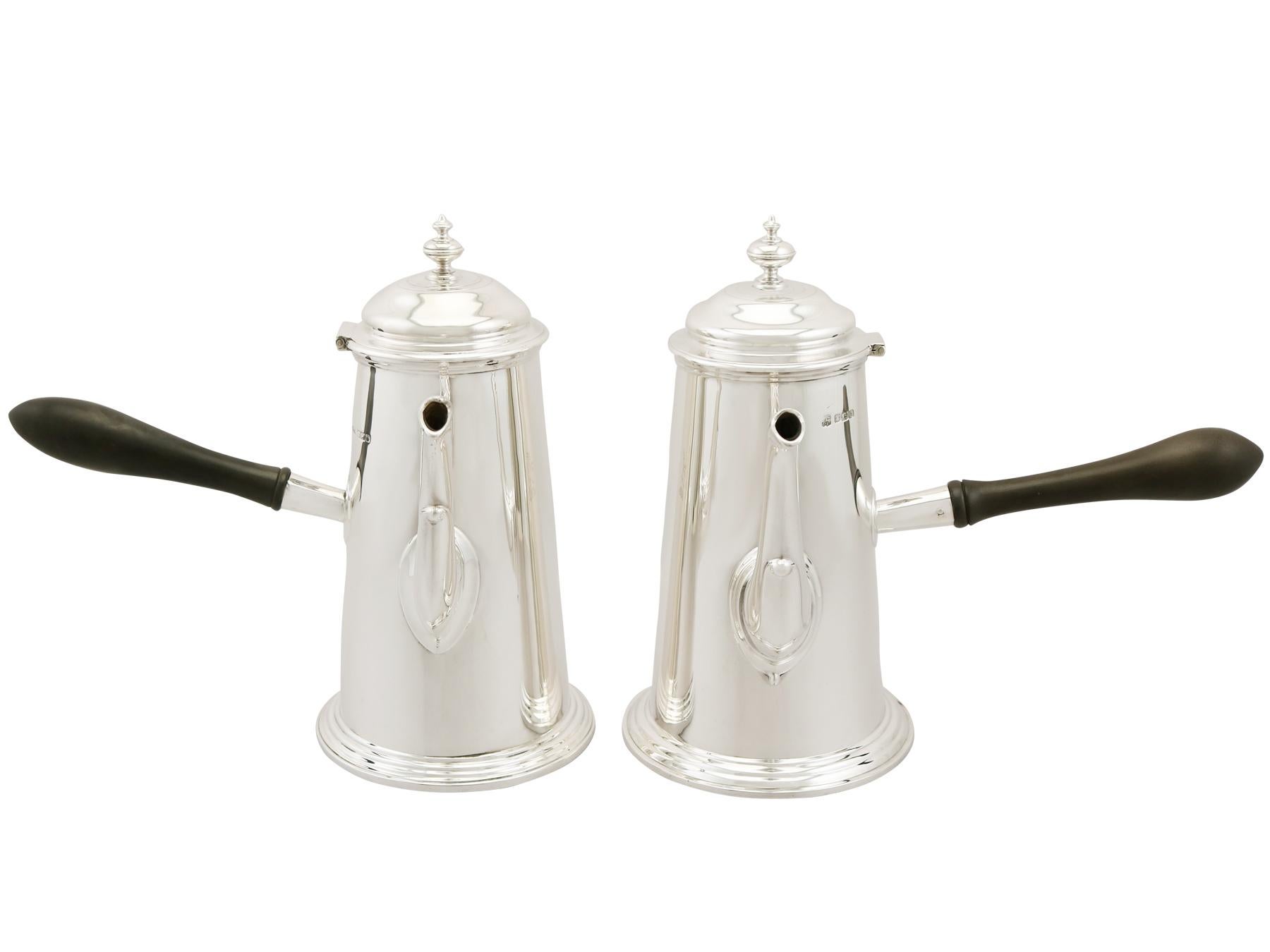 This exceptional antique George V sterling silver café au lait set consists of a coffee pot and hot milk pot.

Each piece has a plain cylindrical tapering form to a stepped spreading foot.

The surface of each piece is plain and embellished with