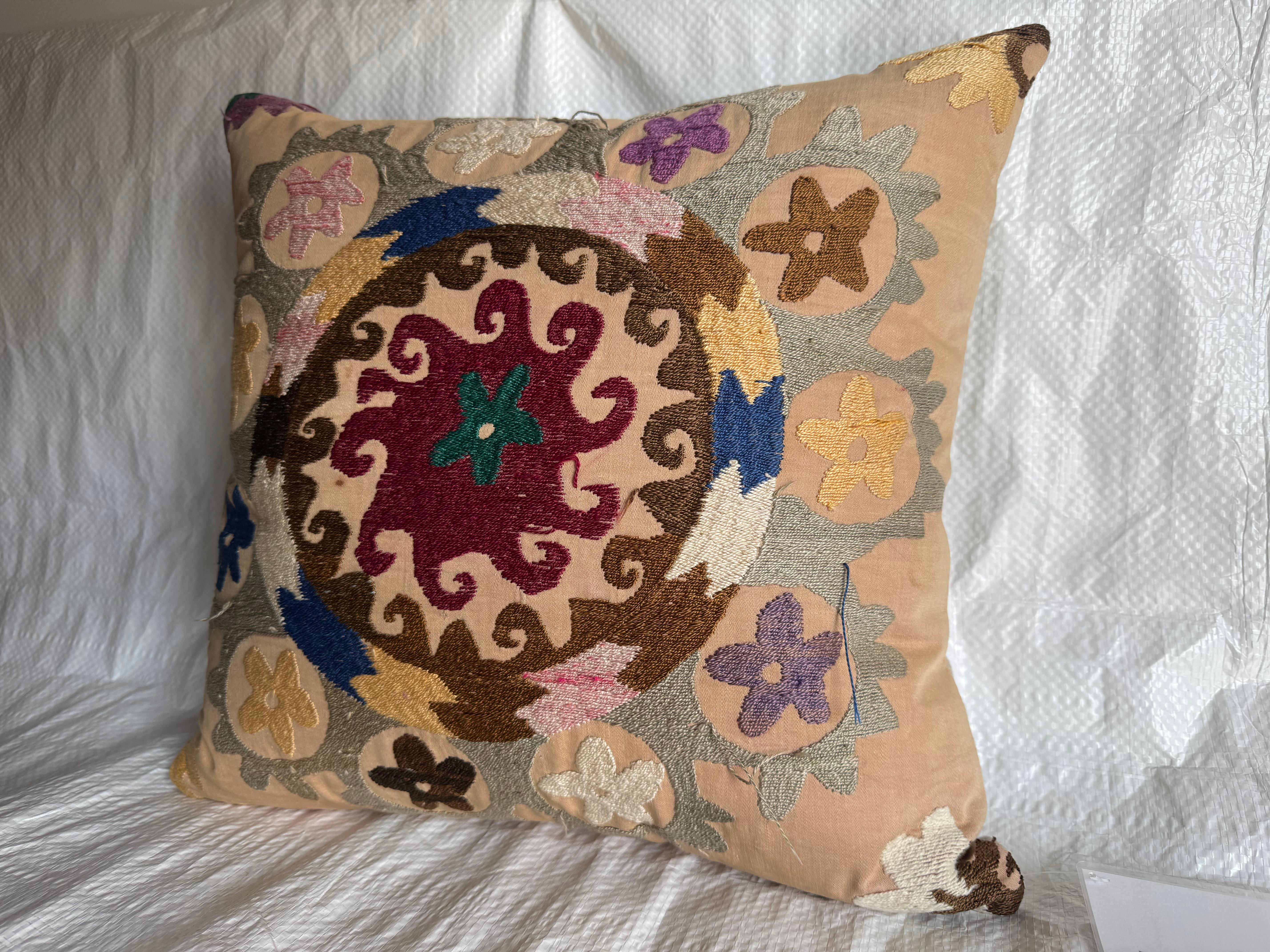 Un oreiller unique fabriqué à partir d'un textile Suzani brodé à la main dans les années 1900. Cette broderie d'Asie centrale présente des motifs floraux audacieux et des médaillons tourbillonnants dans de riches tons de bordeaux, de sarcelle, de