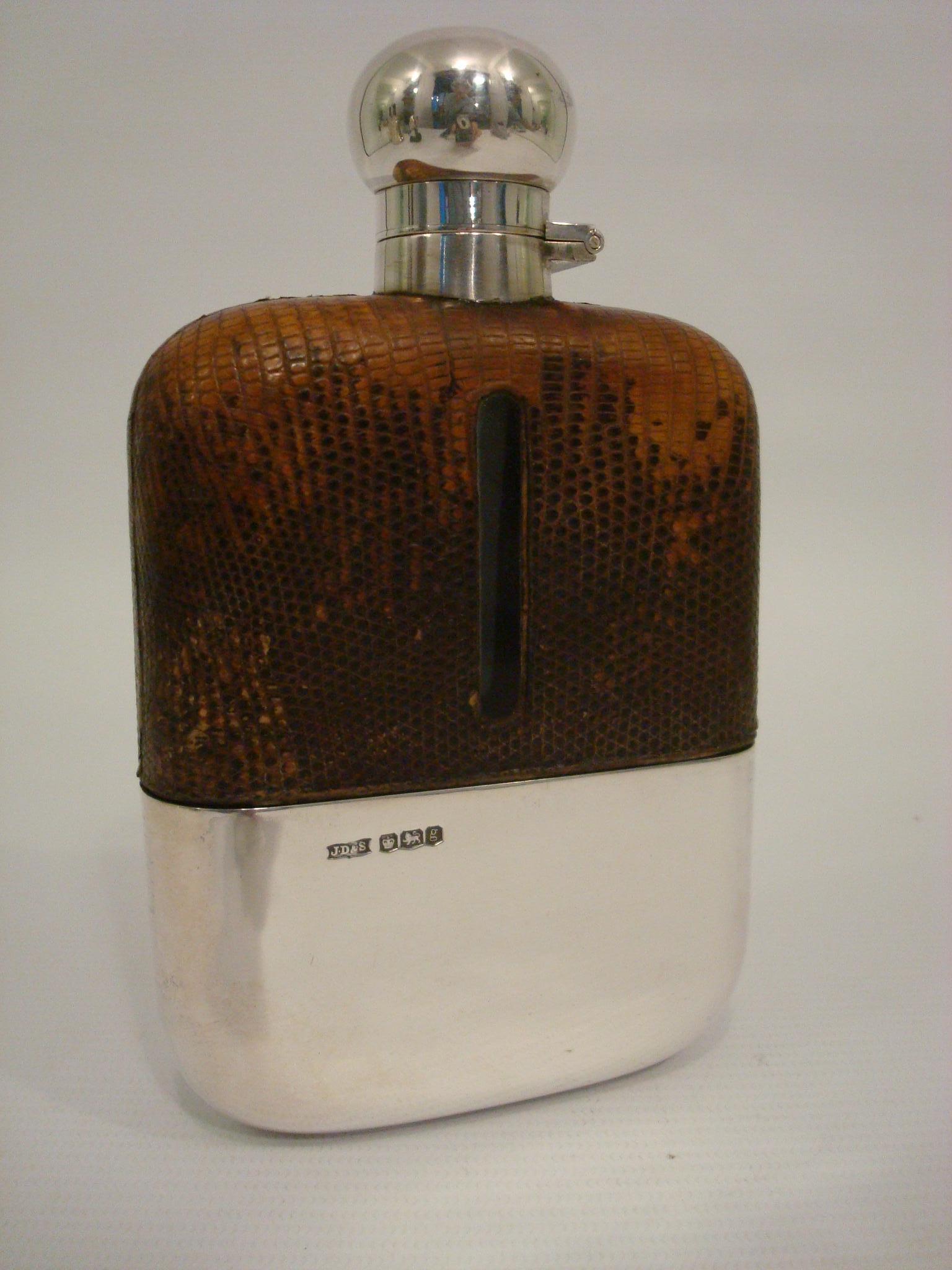A magnificent, fine and impressive, antique George V glass, English sterling silver and Lizard / Snake skin Leather mounted hip flask.
This magnificent antique George V sterling silver hip flask has a rectangular form with rounded corners.
The