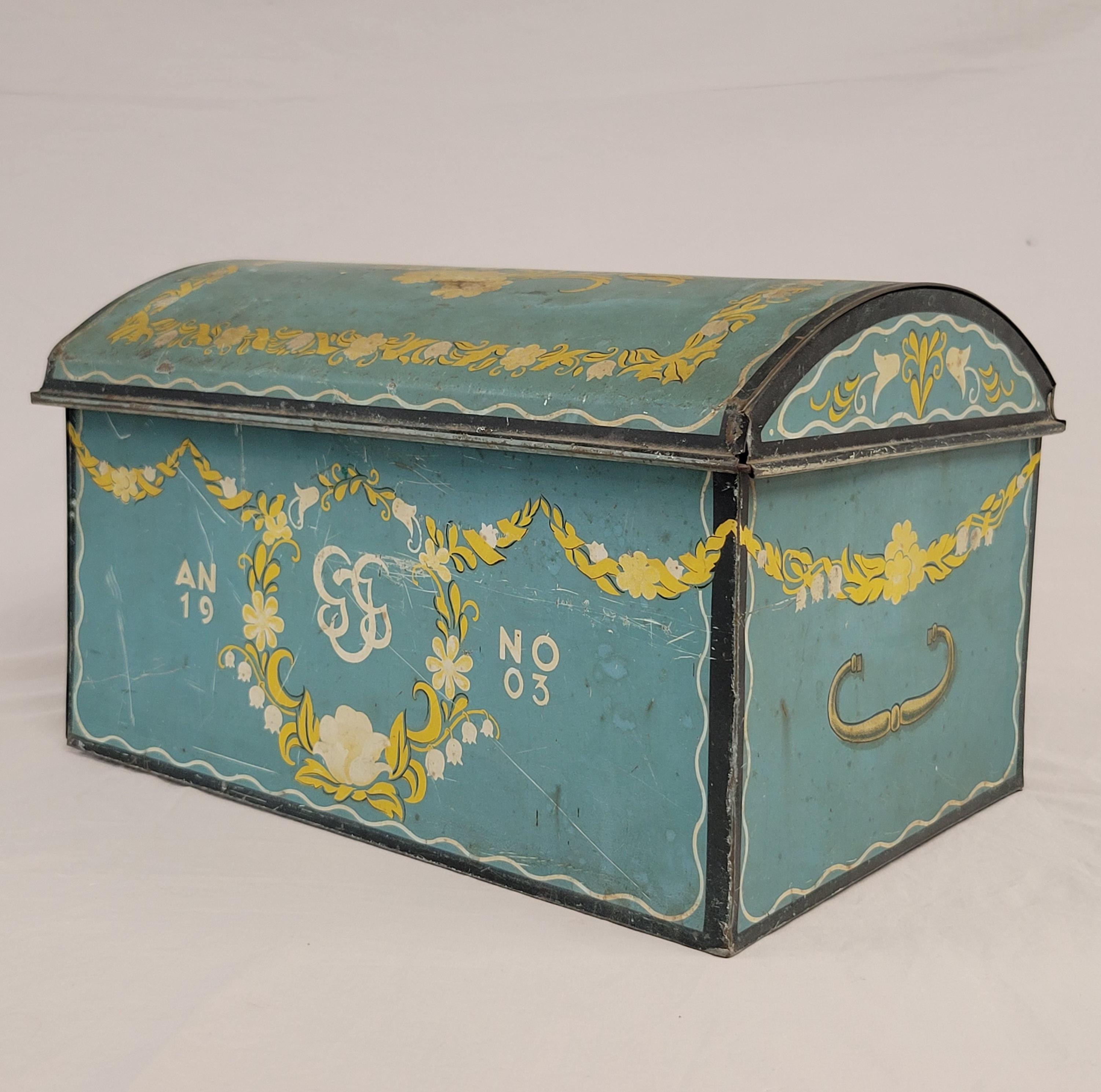 A charming antique 1904 Swedish large dome top trunk shaped chocolate tin would add a beautiful Scandinavian accent to most anywhere in your house. The exterior is a stunning turquoise teal blue accented with yellow and white floral motifs, and