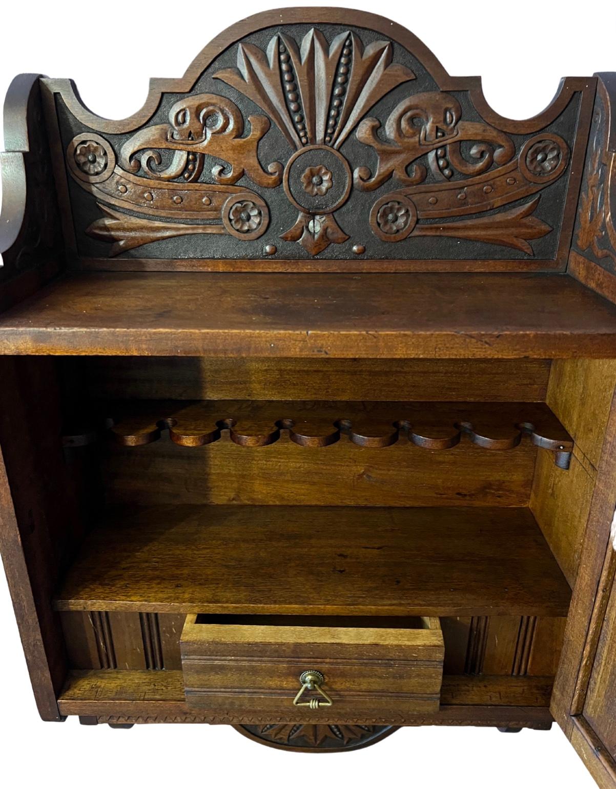 Detailed carvings on all front and sides of cabinet, comes with original key, small shelve on bottom front, sides dated 1905, when opened has 8 pipe holders and drawer, mounts onto the wall, really cool piece to use or even just to display in a man