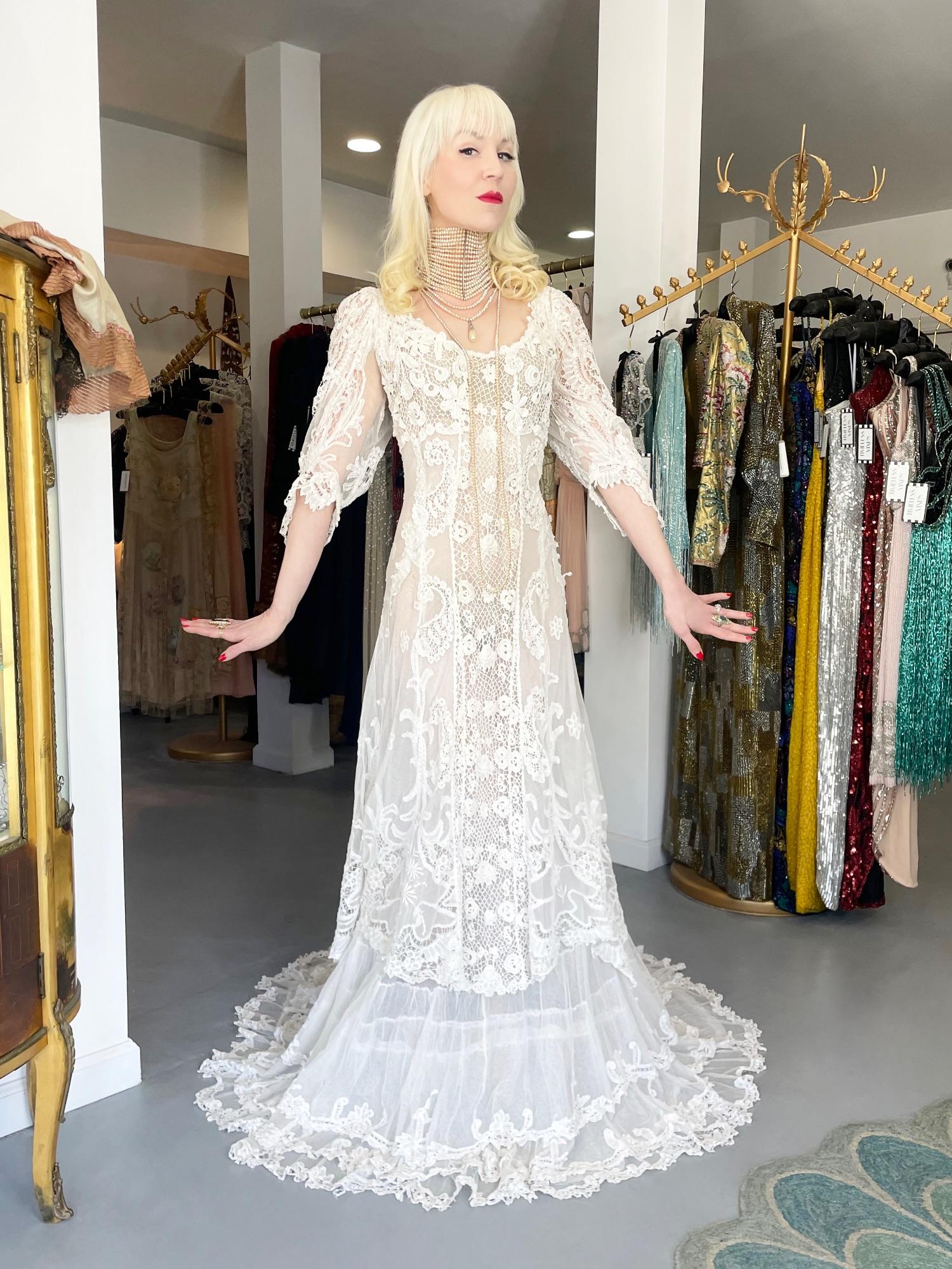 An exceptional ivory white handmade Irish crochet lace and sheer net trained bridal gown from the ethereal Edwardian era. This one-of-a-kind beauty is well over 100 years old but she reads so fresh. This garment represents weeks of custom couture