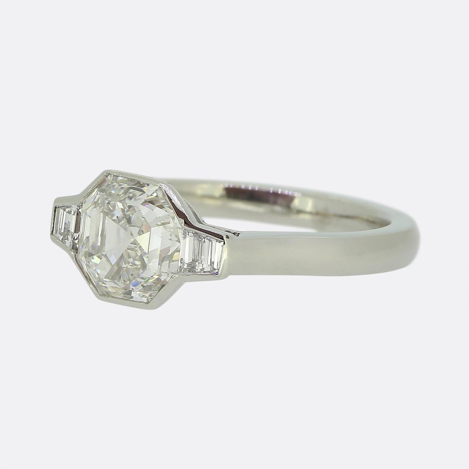 Here we have a stunning diamond ring crafted from luxurious platinum. At its heart lies a captivating 1.91ct asscher cut diamond, exuding brilliance and elegance. Flanking this impressive principal stone are two trapezoid cut diamonds on either