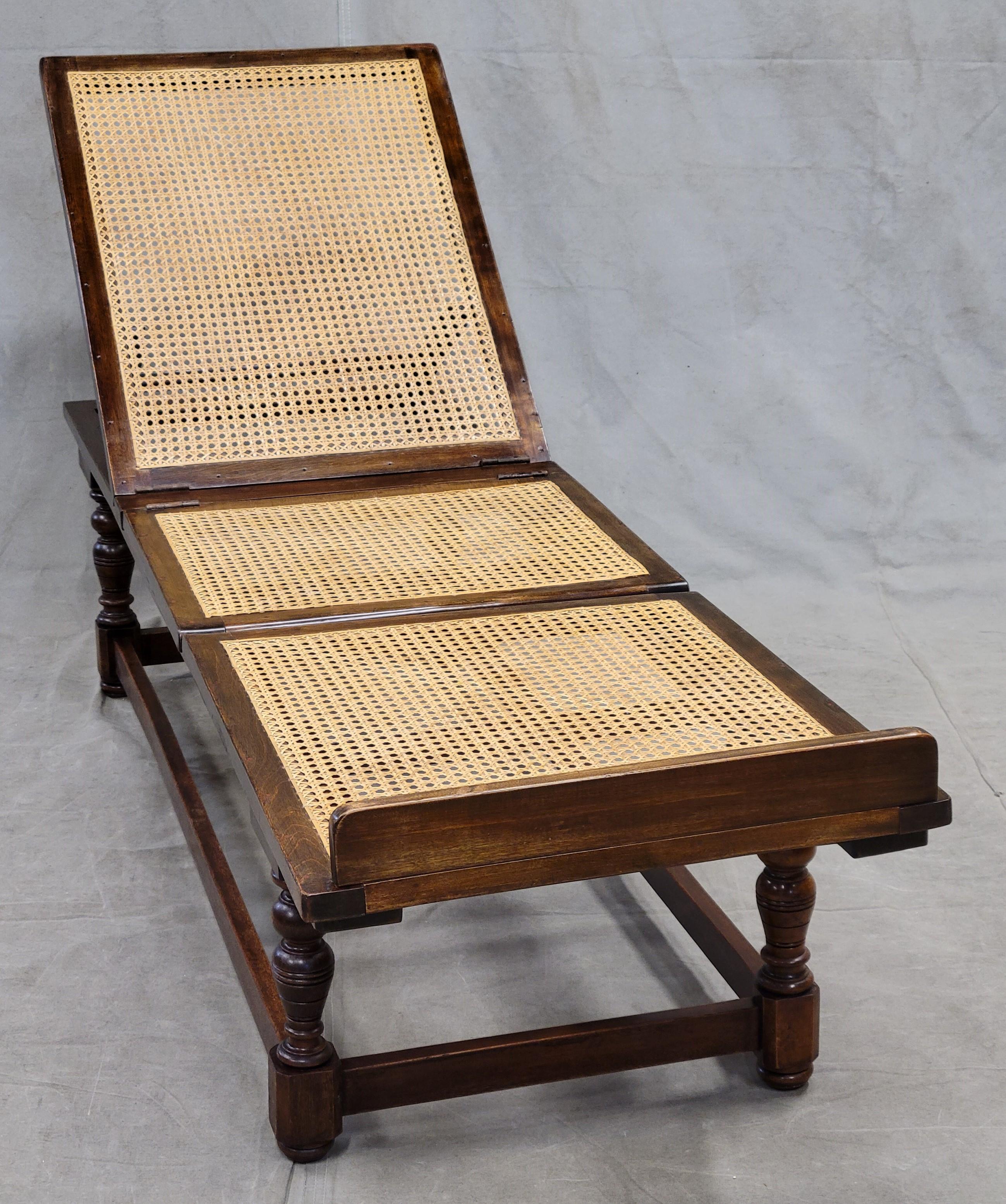 An elegant antique 1910s Leveson & Sons, London, English Colonial mahogany caned folding campaign daybed / deck chair. Hinged and notched for adjustments at the head, knees and feet. Foot rail at bottom end portion. Solid base makes this gorgeous