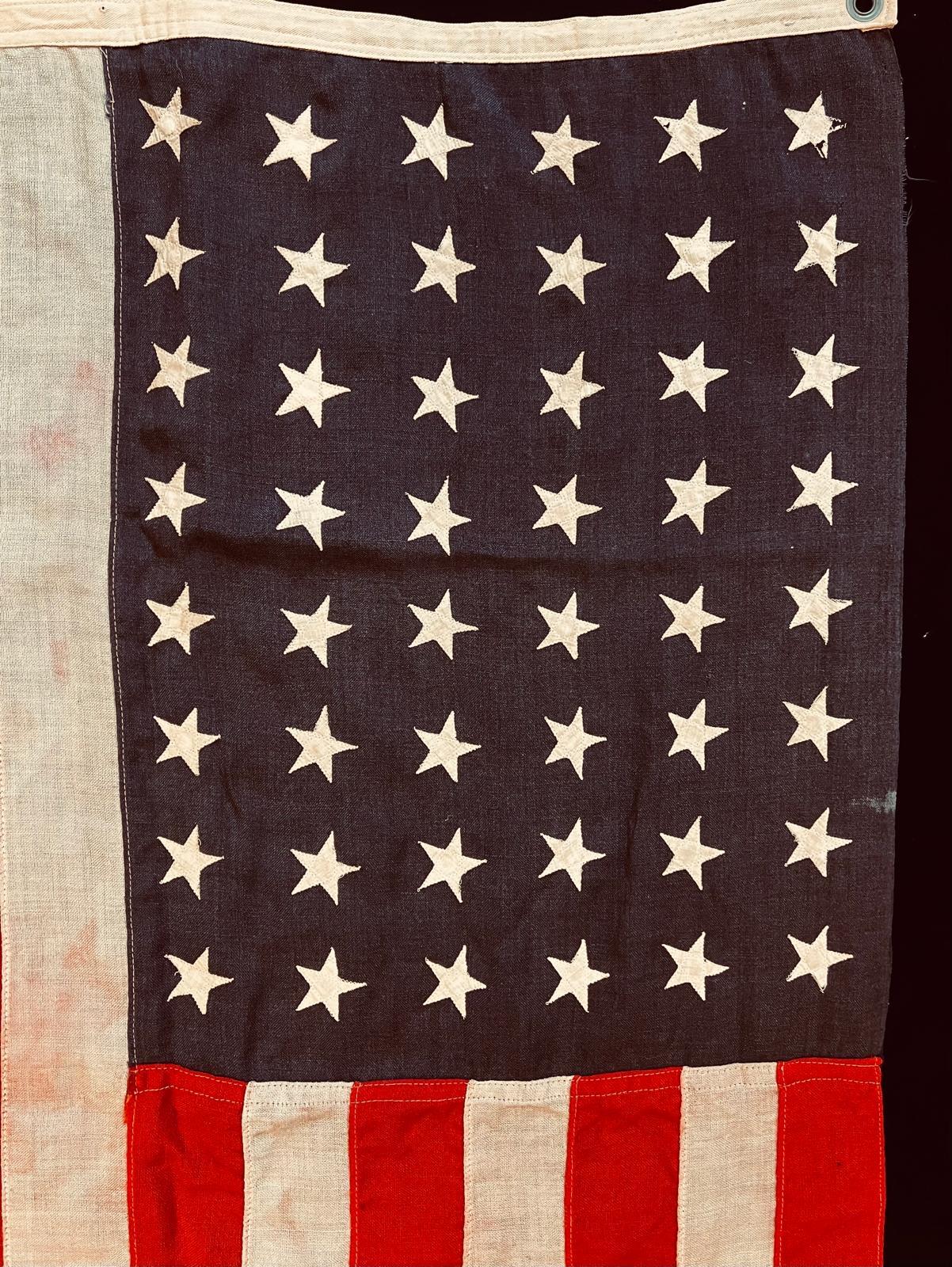 Ce drapeau américain historique exceptionnel, qui mesure 145 cm sur 83 cm, a très probablement été fabriqué avant 1912, si l'on en croit les caractéristiques de son exécution et de ses matériaux. Les étoiles disposées de manière irrégulière, toutes