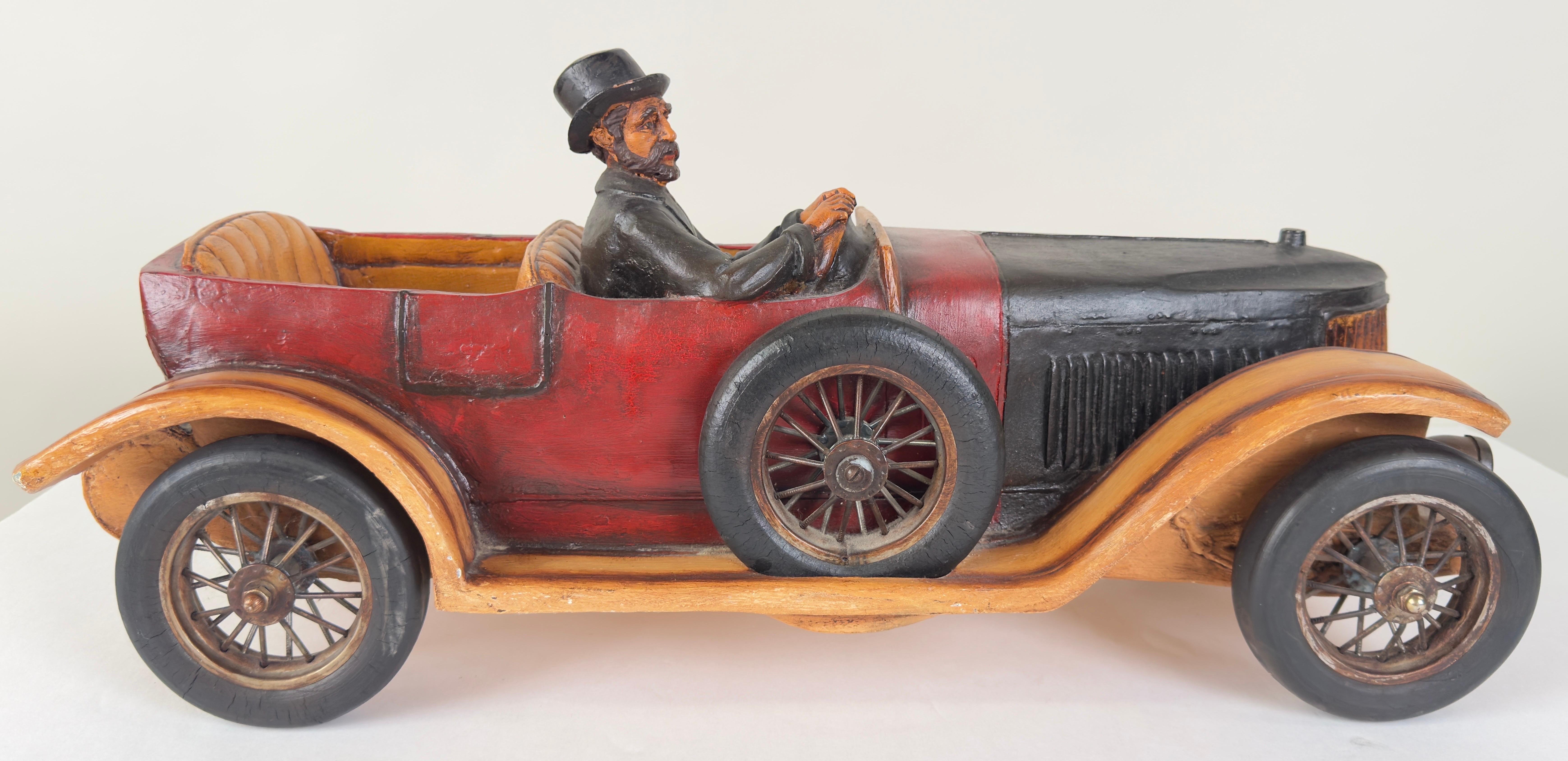 A meticulously crafted 1913  model touring automobile.  The car model features a two-tone color scheme, predominantly black with red accents, which highlights its vintage allure. The body of the car exhibits fine detailing, particularly around the