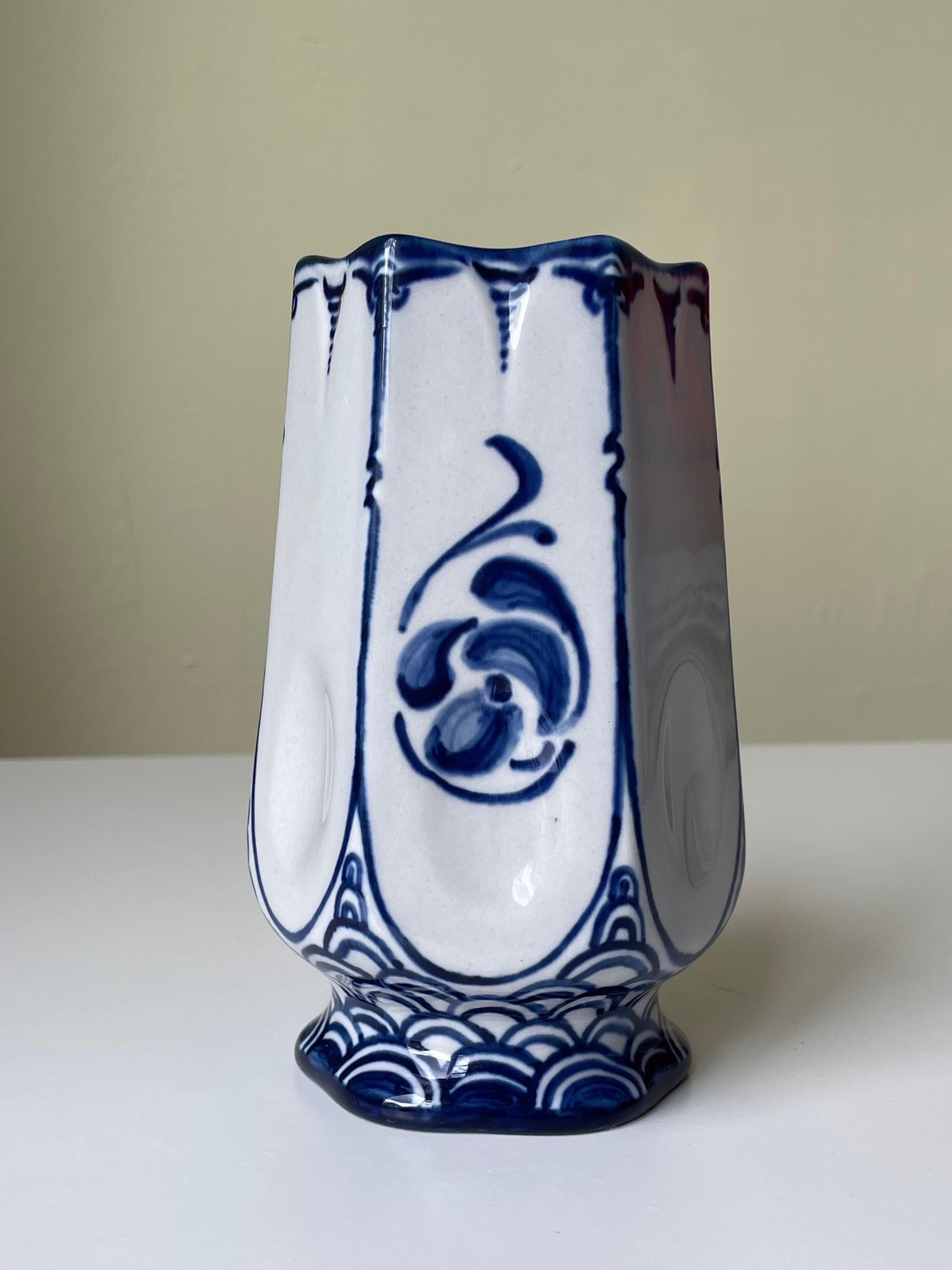 Antique art nouveau hand-decorated porcelain vase by artist Astrid Ewerlöf (1876-1927) for Rörstrand. Manufactured in 1915. Intricate and delicately hand-painted deep blue floral and soft shaped graphic decorations on white base with a light blue