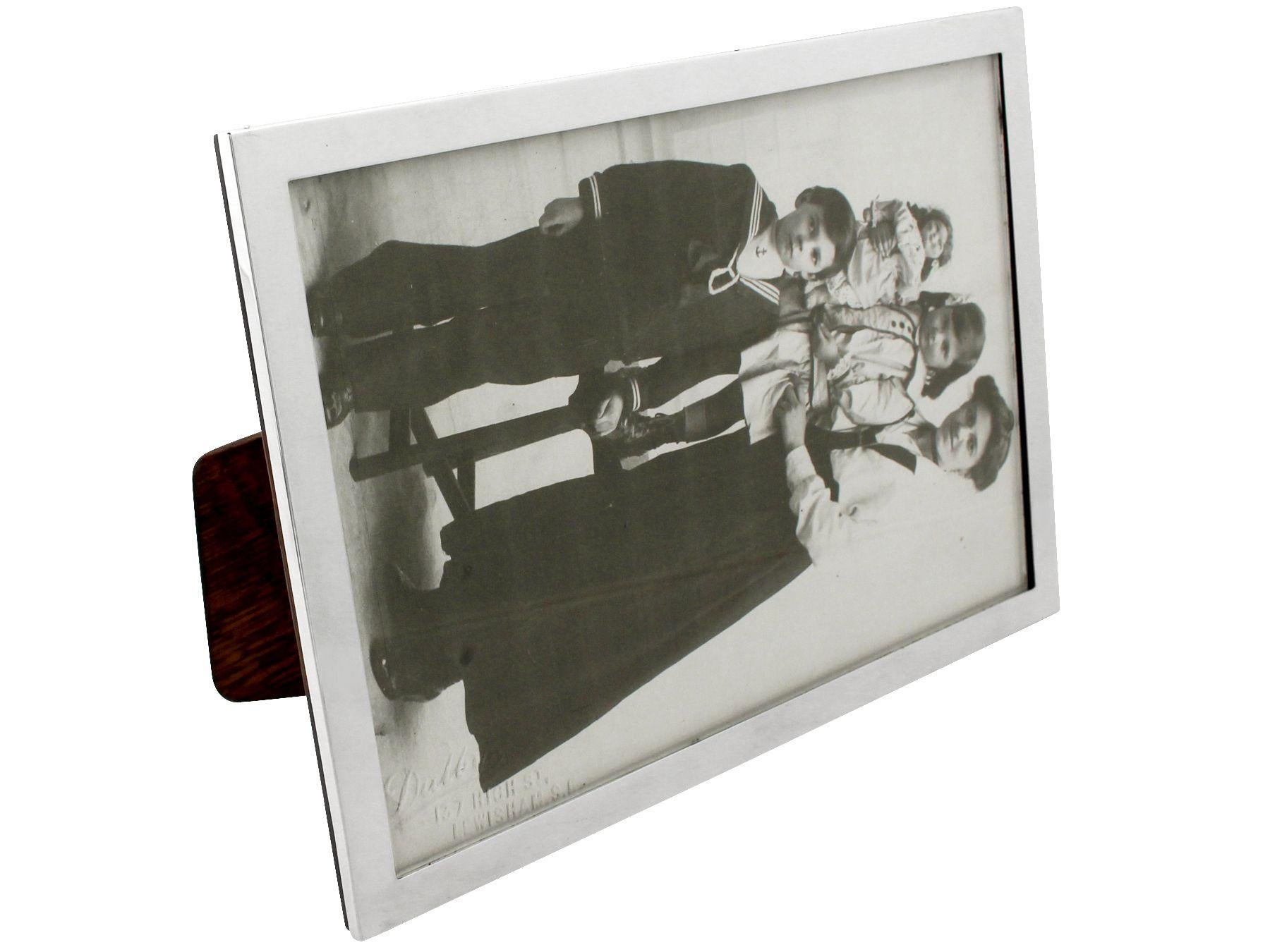 A fine and impressive, large antique George V English sterling silver photograph frame; an addition to our collection of ornamental silverware.

This fine antique sterling silver photo frame has a plain rectangular form.

The surface of this