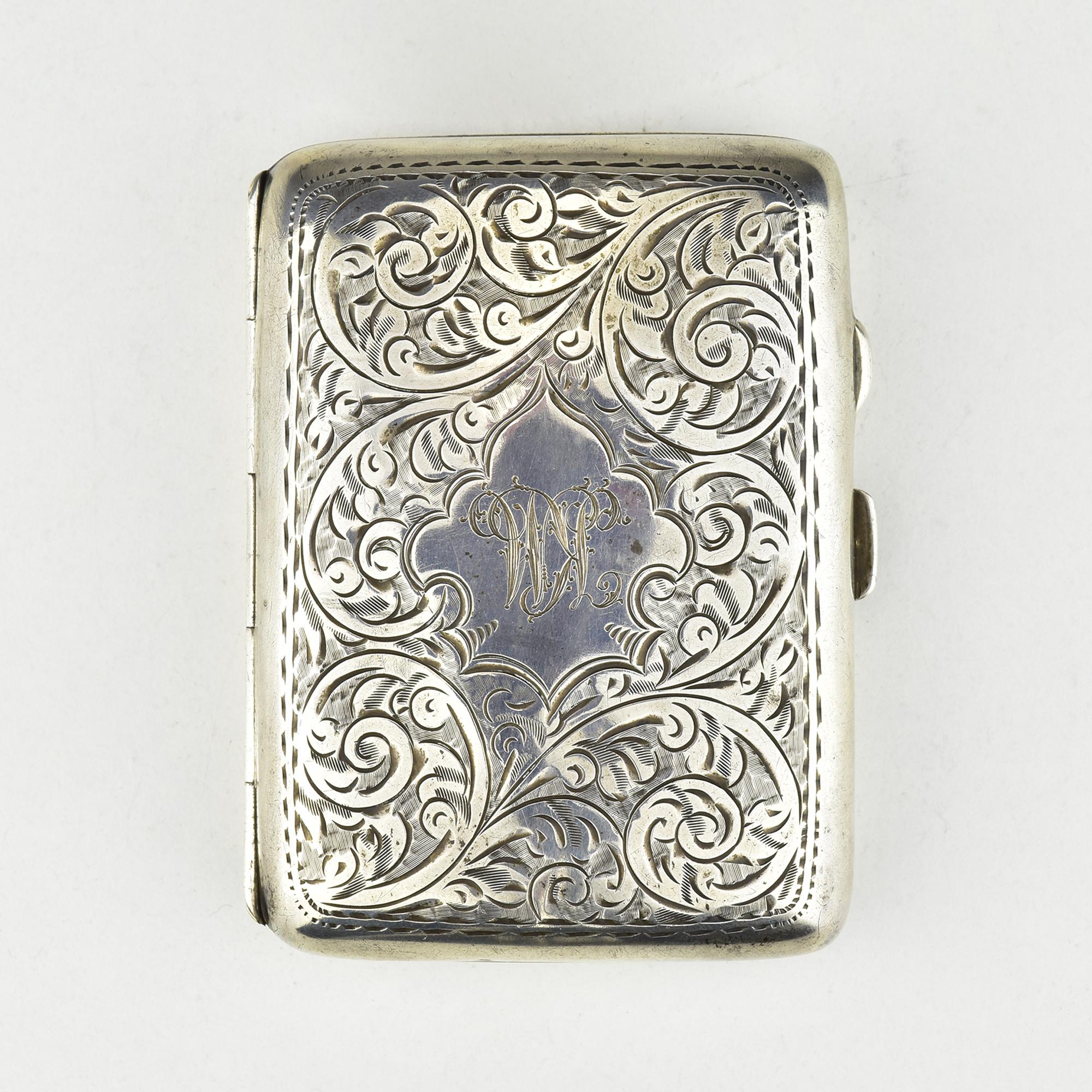 This exquisite antique sterling silver cigarette case was crafted by Joseph Gloster Ltd in Birmingham, dated 1917. The case showcases a fine chiseled botanical scrollwork design on both sides, with elegant swirling foliage patterns finely engraved