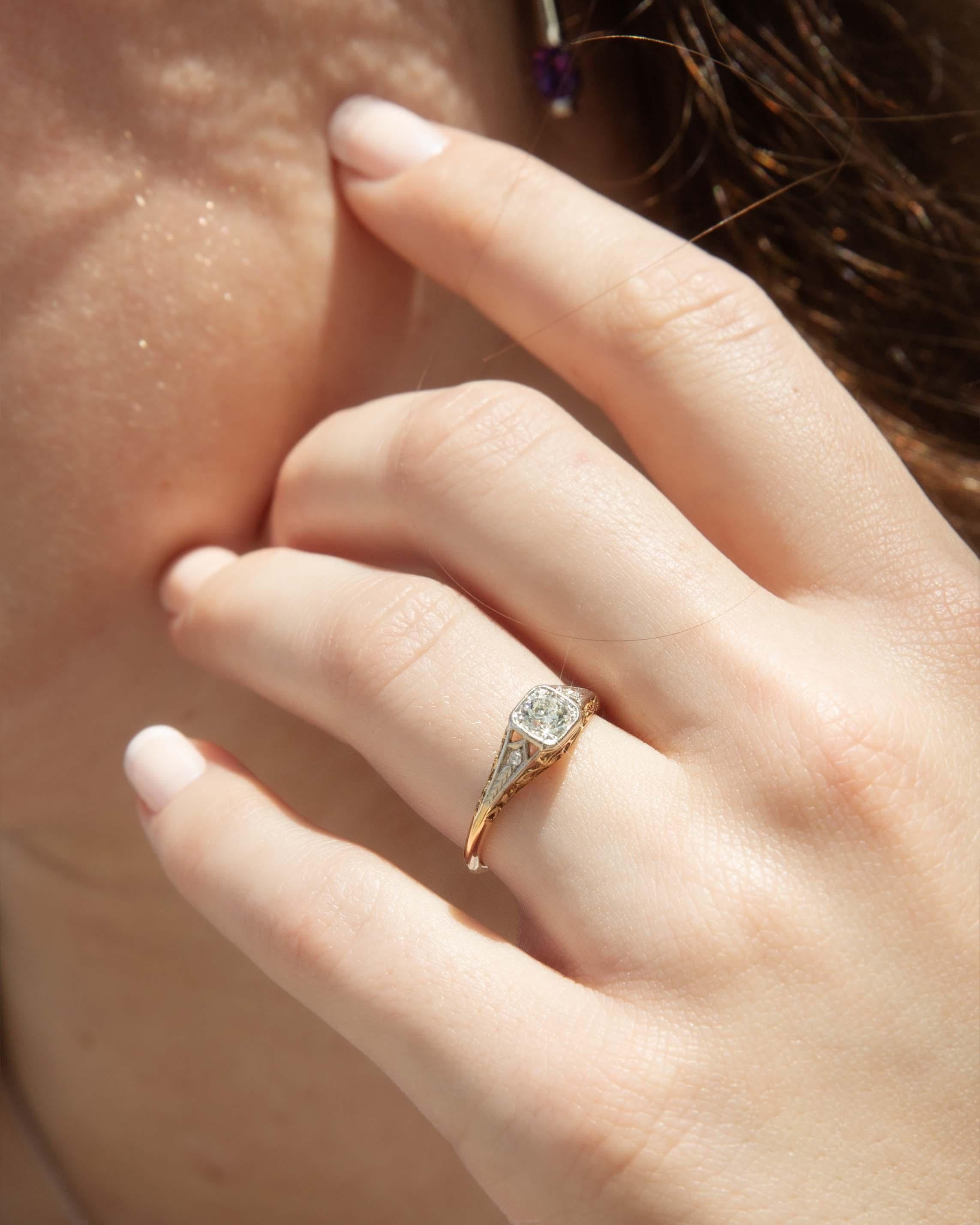 In her heart, the antique Greer Diamond Ring whispers of elegance unfold like the petals of a rare bloom. Platinum intertwines with 18 carat gold, cradling exquisite old cut diamonds that dance with captured light, casting ethereal glows. She