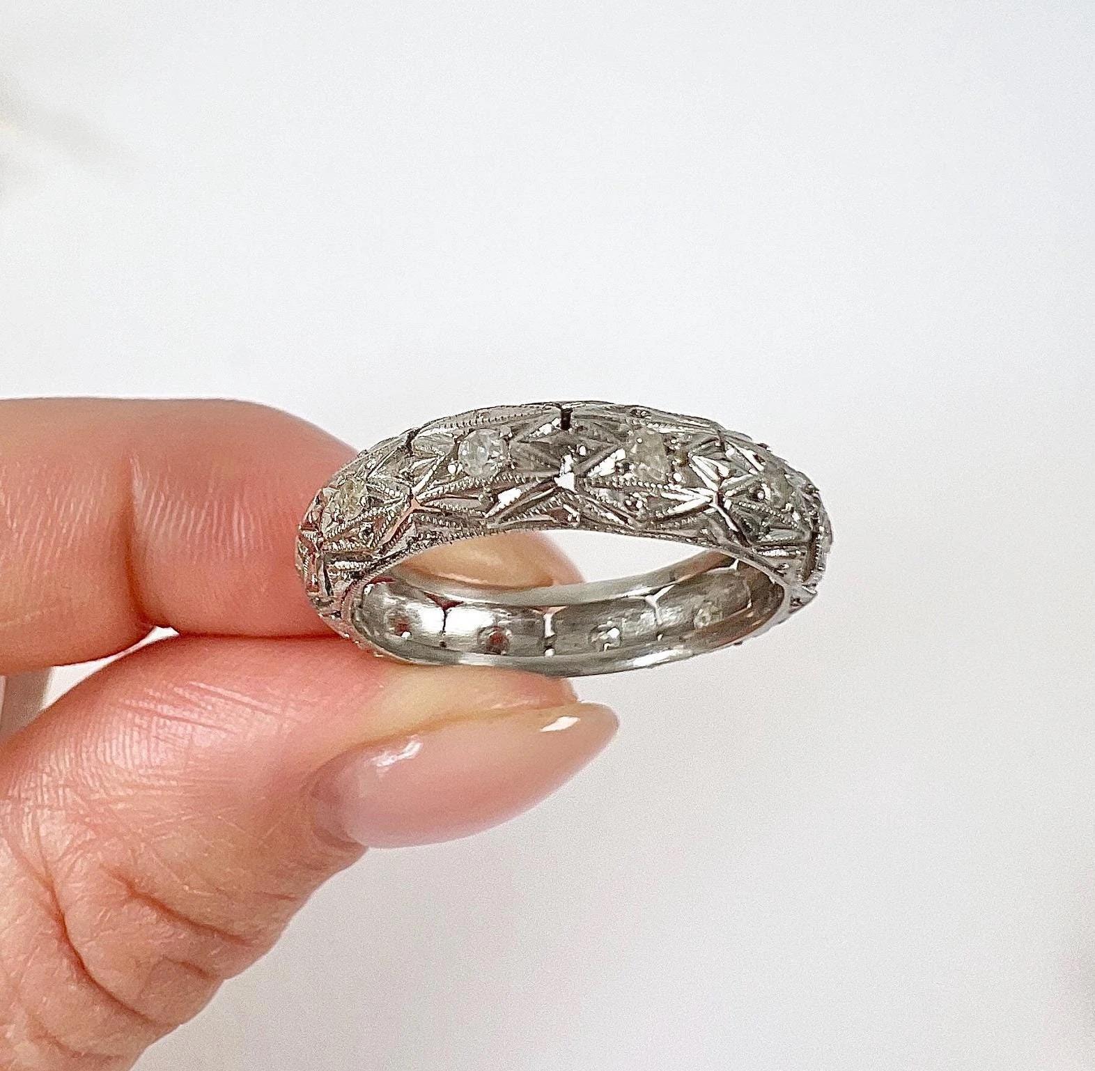 Antique Platinum Band

Circa 1920s

Behold a magnificent Art Deco masterpiece from the 1920s! This exquisite antique platinum diamond wedding ring is a true work of art, meticulously handcrafted with an engraved hexagon geometric filigree pattern,